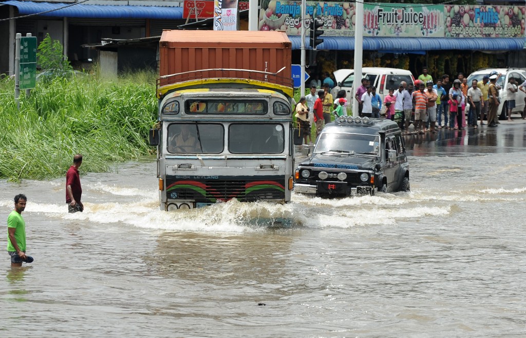 Sri Lankan commuters drive through floodwaters along an expressway in the suburb of Athurugeriya in capital Colombo on May 18, 2016. Rescue workers in Sri Lanka searched for 16 people missing May 18 after landslides buried several homes following three days of heavy rain, police said. / AFP PHOTO / LAKRUWAN WANNIARACHCHI