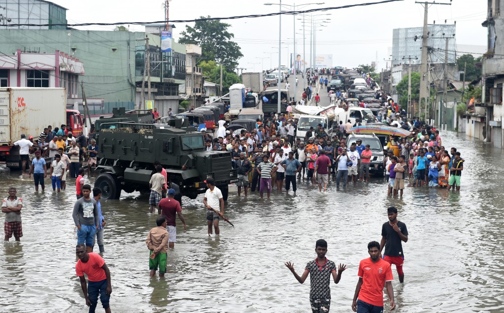 Sri Lankan residents make their way through floodwaters in Colombo on May 19, 2016. Sri Lankan troops recovered seven more bodies from piles of mud on May 19, raising the death toll from rain-triggered landslides that buried two villages to 24, an official said. At least 45 people have died on the island in weather-related disasters since the weekend. / AFP PHOTO / ISHARA S.KODIKARA