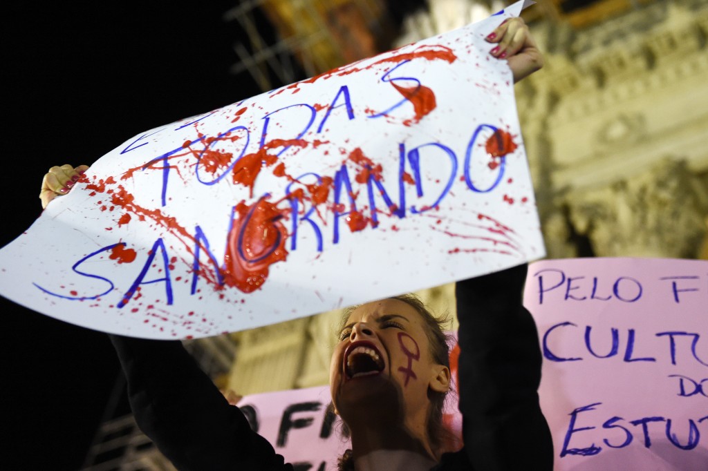 Brazilians protest in front of the Legislative Assembly of Rio de Janeiro (ALERJ) on May 27, 2016, against a gang-rape of a 16-year-old girl.  Brazilian police on Friday were investigating the gang-rape of a 16-year-old girl whose attackers boasted about it by posting an online video of her that has horrified the country. Online social networks erupted with outrage over the video posted on Wednesday featuring the girl naked on a bed and the apparent rapists bragging that she had been raped by more than 30 men. / AFP PHOTO / VANDERLEI ALMEIDA