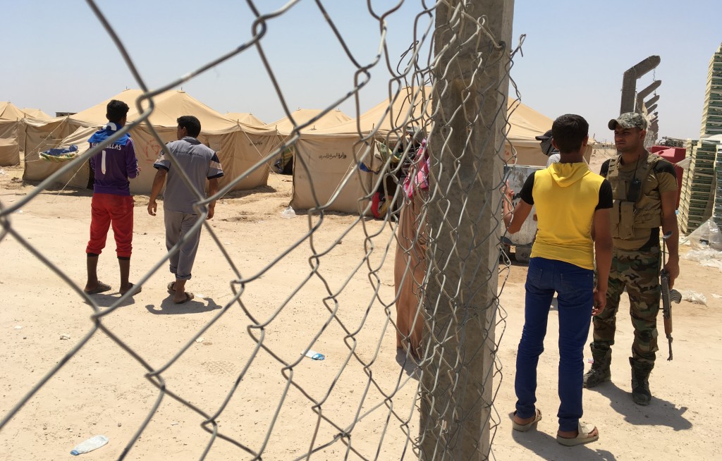 A member of the Iraqi armed forces stands guard at the entrance of a newly-opened camp in the government-held town of Amriyat al-Fallujah 50 kilometres (30 miles) southwest of Baghdad, on May 29, 2016, which was set up to shelter people fleeing violence around the city of Fallujah. The Norwegian Refugee Council, which runs the camp in Amriyat al-Fallujah, says around 3,000 people have managed to flee the area and reach displacement camps since Iraqi forces launched an operation against the Islamic State a week ago. The biggest wave of arrivals so far was Saturday night and included mostly exhausted and hungry women and children. / AFP PHOTO / Jean Marc MOJON