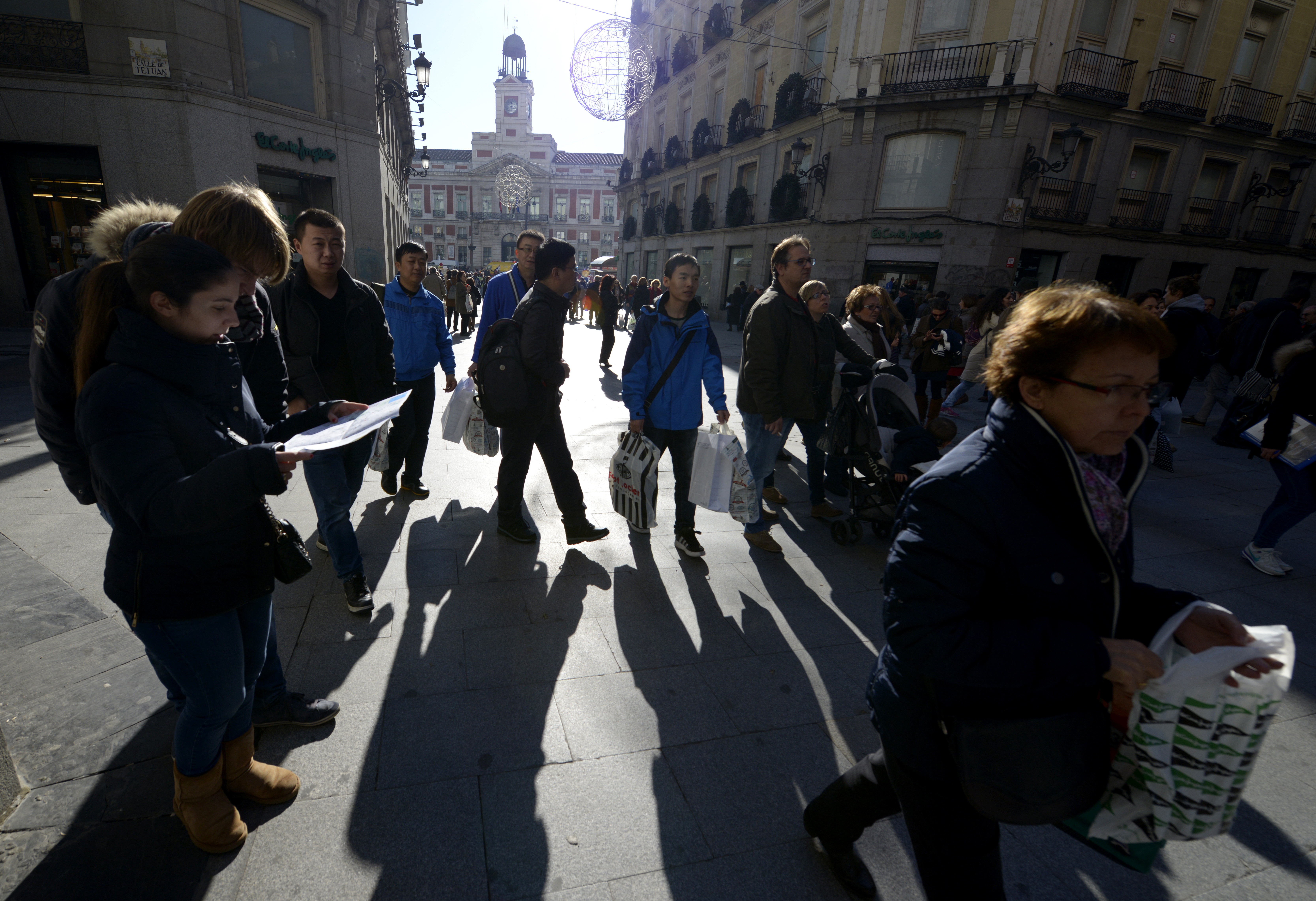 Tourists and city-dwellers carrying shopping bags walk along a paved street near Puerta del Sol in Madrid on December 16 , 2014.  AFP PHOTO/ GERARD JULIEN / AFP PHOTO / GERARD JULIEN