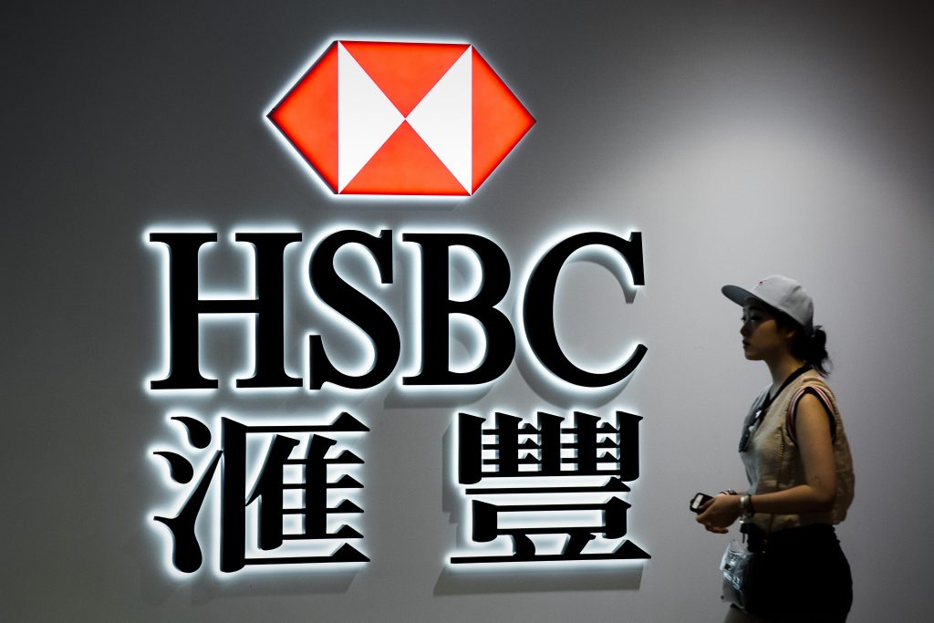 A woman walks past a logo of the HSBC bank in Hong Kong on August 3, 2015. Banking giant HSBC was to release its six-month financial results on August 3, 2015. AFP PHOTO / Philippe Lopez / AFP PHOTO / PHILIPPE LOPEZ