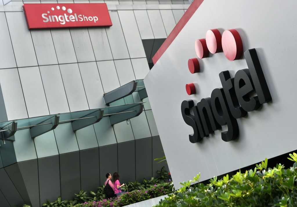 A couple walks towards the Singapore Telecommunications (Singtel) building in Singapore on February 12, 2016.  Singtel reported a 1.7 per cent fall in third-quarter net profit of 683 million US dollar for the three months ended December, compared with 694 million US dollar a year ago, as adverse currency movements and investments offset growing mobile data usage by its customers.  AFP PHOTO / ROSLAN RAHMAN / AFP PHOTO / ROSLAN RAHMAN