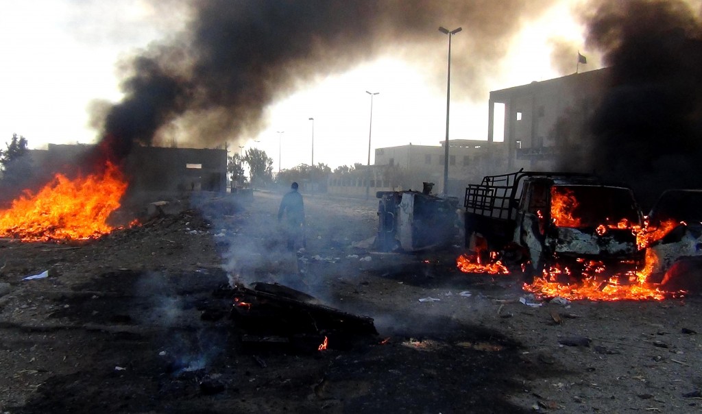 A man walks amidst smoke and fire following a reportedly air strike by Syrian government forces in the Islamic State (IS) group controlled Syrian city of Raqa, on November 25, 2014. A string of Syrian regime air strikes on the Islamic State group's self-proclaimed capital Raqa killed at least 63 people, more than half of them civilians, a monitor said. The air strikes were the deadliest by President Bashar al-Assad's air force against Raqa since the Sunni extremist IS seized control of the city last year. AFP PHOTO/RMC/STR / AFP PHOTO / Raqa Media Center / STR