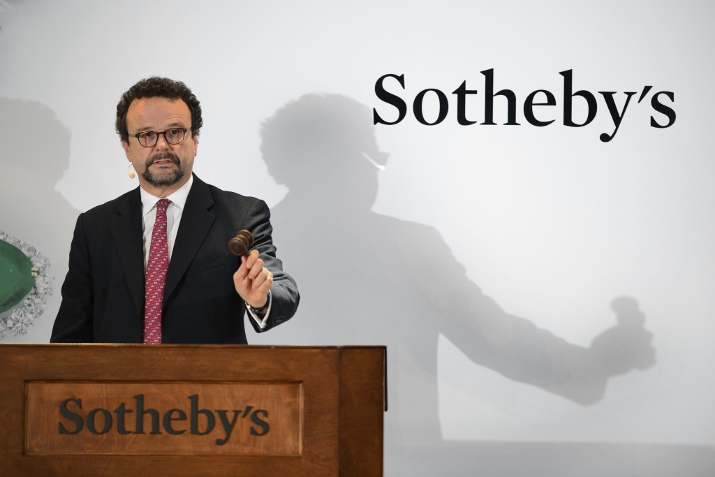 Head of Sotheby's international jewelery division, David Bennett holds the hammer during a "Magnificent Jewels and Noble Jewels" sales at the auction house on November 11, 2015 in Geneva. All eyes will turn to Sotheby's when its prized lot, dubbed "Blue Moon" with an estimated sale price between USD 35-55 million (about 32 597 560 to 51 224 737 euros) that will aim to shatter the record for a stone sold at an auction.  AFP PHOTO / FABRICE COFFRINI / AFP PHOTO / FABRICE COFFRINI