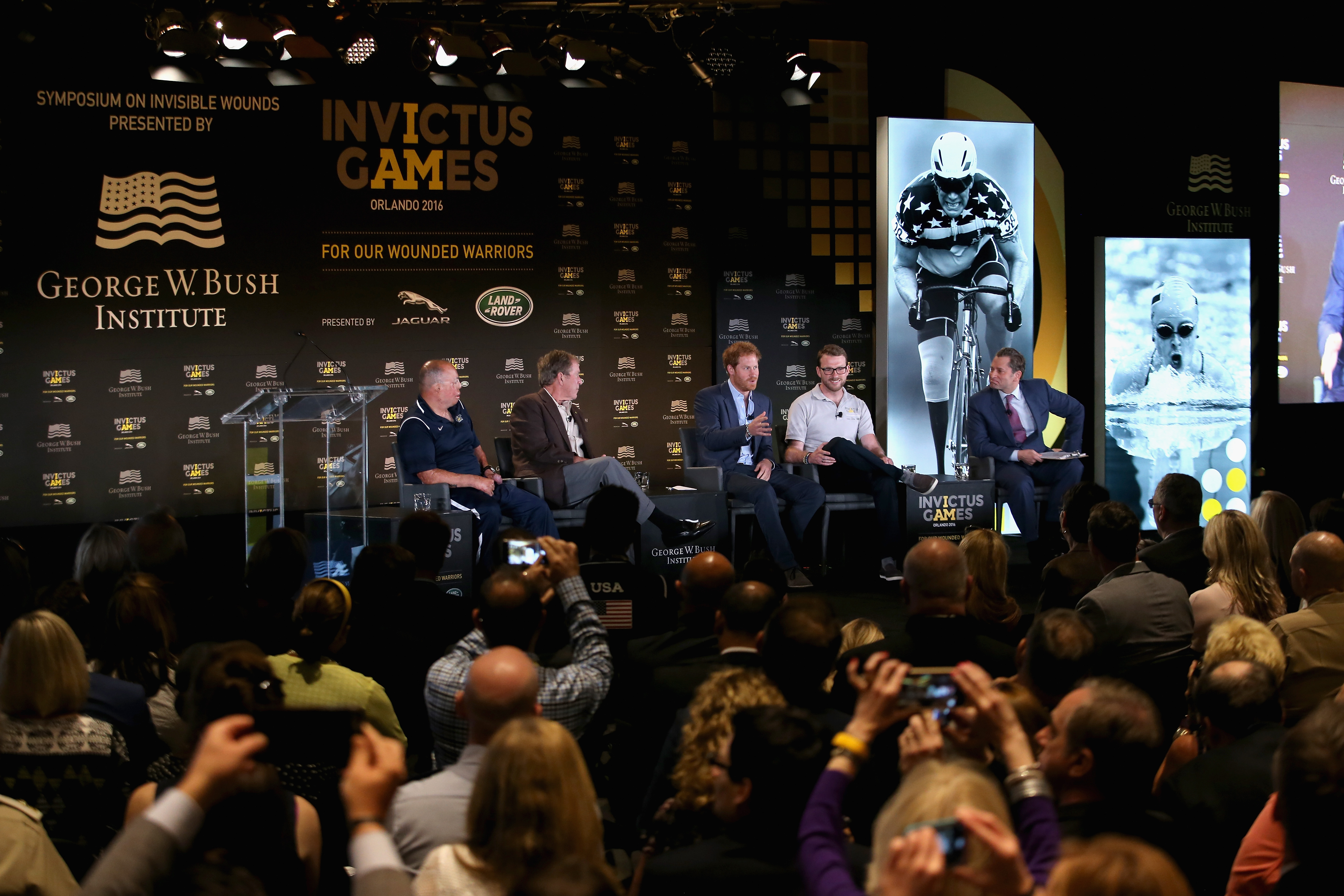 ORLANDO, FL - MAY 08: Prince Harry, Former President George W Bush Royal Marine veteran JJ Chalmers (R) and Air Force Technical Sgt. Israel Del Toro (L) talk at a Symposium of Invisable Wounds at the Shades of Green resort at Invictus Games Orlando 2016 at ESPN Wide World of Sports on May 8, 2016 in Orlando, Florida. Prince Harry, patron of the Invictus Games Foundation is in Orlando ahead of the opening of Invictus Games which will open on Sunday. The Invictus Games is the only International sporting event for wounded, injured and sick servicemen and women. Started in 2014 by Prince Harry the Invictus Games uses the power of Sport to inspire recovery and support rehabilitation. Chris Jackson/Getty Images for Invictus/AFP