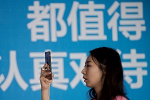 (File photo) A woman uses her smartphone to take a picture during the Global Mobile Internet Conference (GMIC) at the National Convention Centre in Beijing on April 28, 2016. GMIC hosts mobile executives, entrepreneurs, developers, and investors from around the world. / AFP PHOTO / NICOLAS ASFOURI
