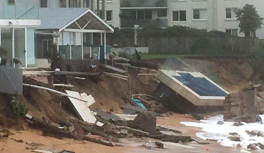An inground pool lies on the beach next to damaged houses after a severe storm at Collaroy on Sydney's northern beaches on June 6, 2016. Wild weather which has smashed into Australia's east coast and whipped up giant waves on Sydney beaches has left at least three people dead and others missing, police as the clean-up began. / AFP PHOTO / BRUCE CLEMENT / ----EDITORS NOTE ----RESTRICTED TO EDITORIAL USE MANDATORY CREDIT " AFP PHOTO / BRUCE CLEMENT" NO MARKETING NO ADVERTISING CAMPAIGNS - DISTRIBUTED AS A SERVICE TO CLIENTS - NO ARCHIVES
