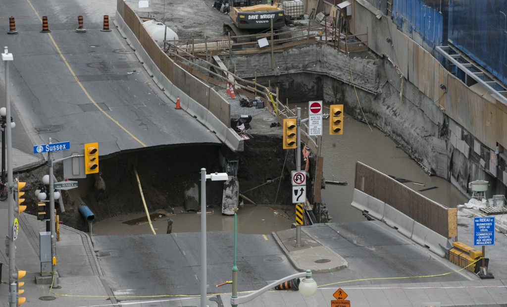 A large portion of Rideau Street in downtown Ottawa, Ontario is seen caved in, causing a massive sinkhole that knocked out power to the majority of the downtown area on June 8, 2016.       The massive sinkhole formed next to a shopping mall in downtown Ottawa, caused a gas leak and forced the evacuation of all nearby businesses. / AFP PHOTO / (Chris Roussakis/AFP) / Chris Roussakis