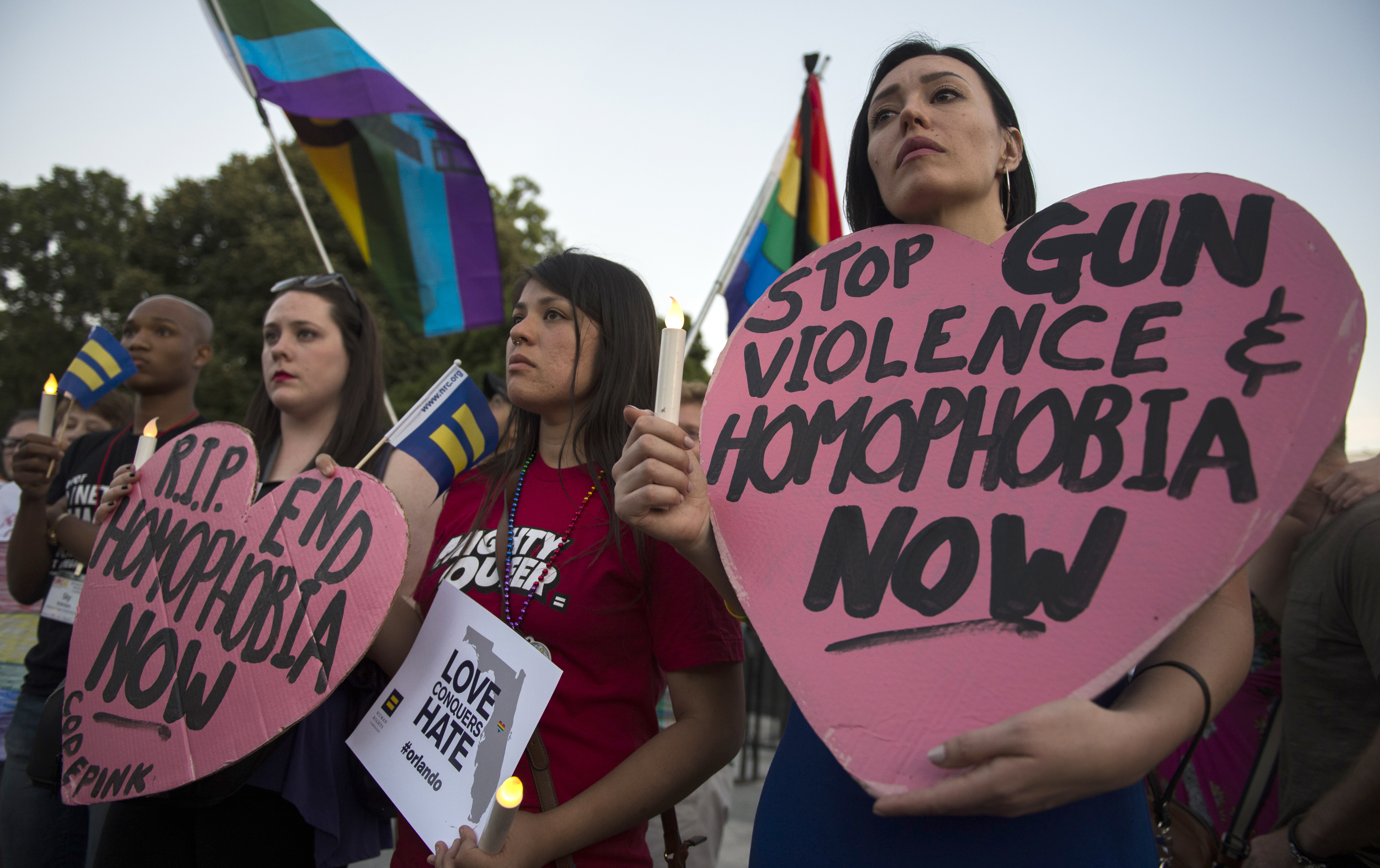 Mourners hold up signs during a vigil in Washington, DC on June 12, 2016, in reaction to the mass shooting at a gay nightclub in Orlando, Florida.  Fifty people died when a gunman allegedly inspired by the Islamic State group opened fire inside a gay nightclub in Florida, in the worst terror attack on US soil since September 11, 2001. / AFP PHOTO / Andrew Caballero-Reynolds