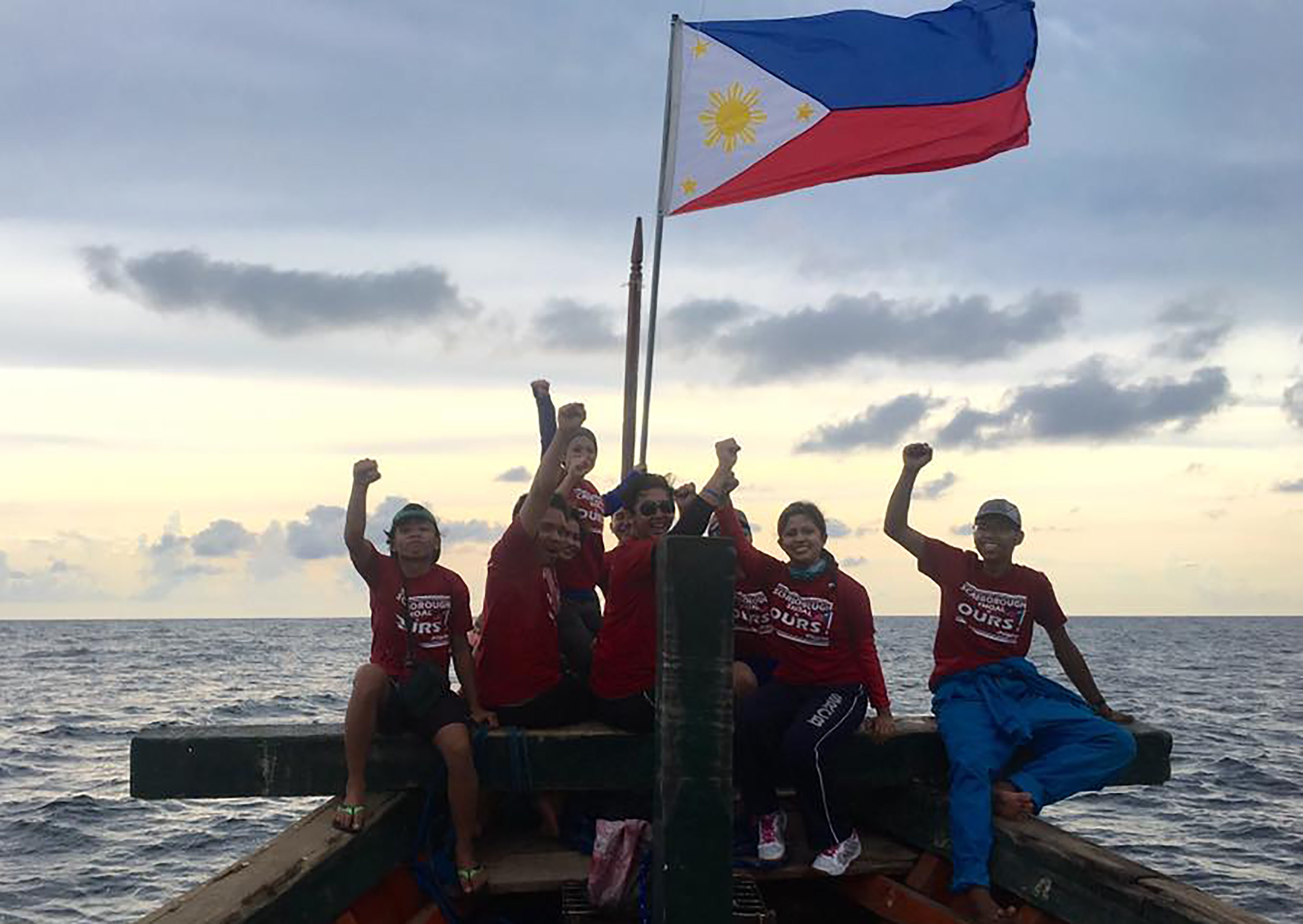 This undated handout photo taken from the Facebook account of Kalayaan Atin Ito (Kalayaan This Is Ours), a group of Filipino activists, made available to Agence France-Presse on June 13, 2016 shows a Filipino activists posing for photo at the bow of thei vessel next to a Philippine flag at Scarborough shoal. Filipino protesters said on June 13, 2016 China's coast guard blocked and sprayed them with water as their small group sailed to a Chinese-controlled South China Sea shoal to mark Philippine independence day. / AFP PHOTO / KALAYAAN ATIN TIO / HO / -----EDITORS NOTE --- RESTRICTED TO EDITORIAL USE - MANDATORY CREDIT "AFP PHOTO / KALAYAAN ATIN TIO" - NO MARKETING - NO ADVERTISING CAMPAIGNS - DISTRIBUTED AS A SERVICE TO CLIENTS - NO ARCHIVES