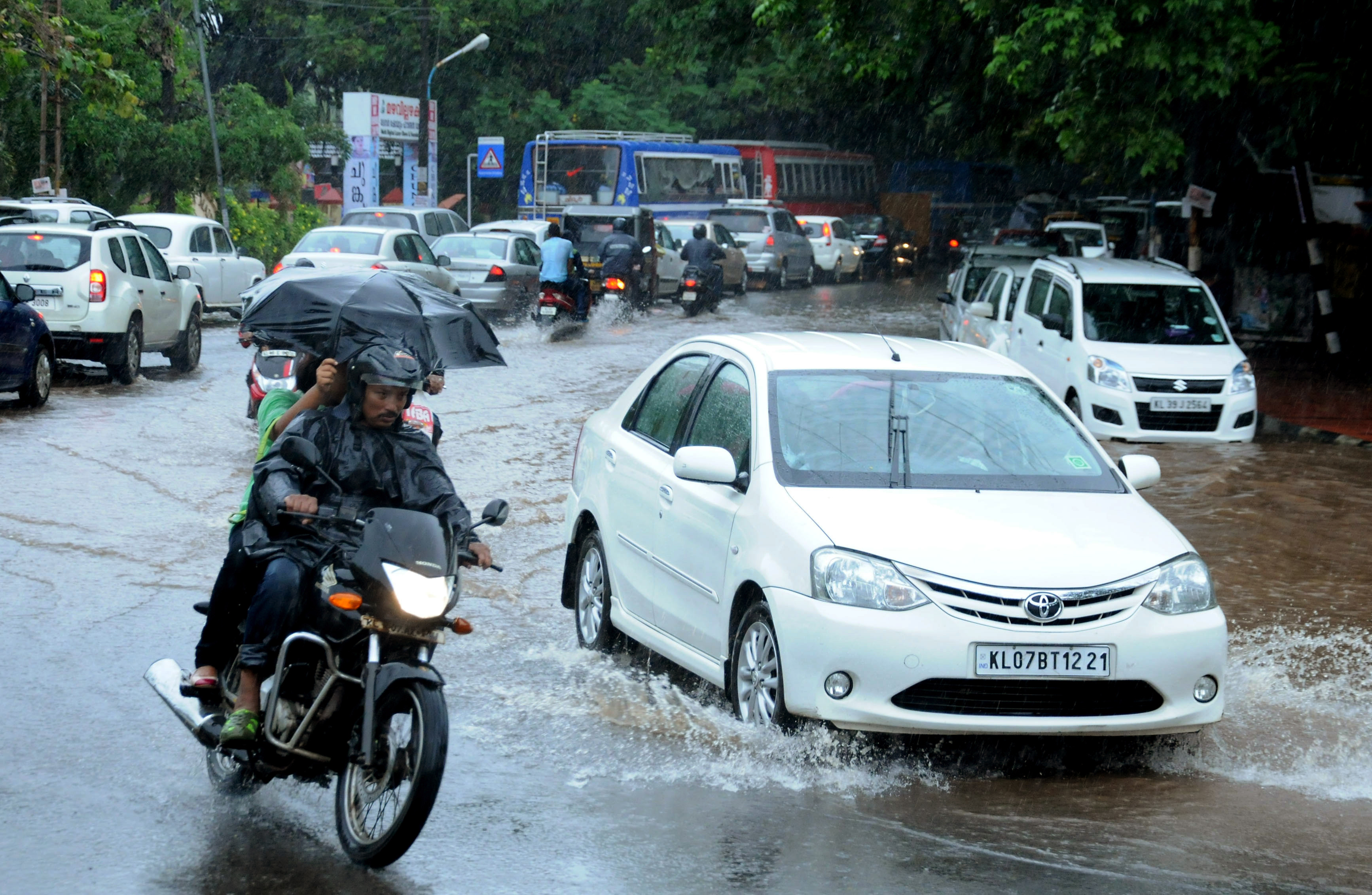 (FILES) This file photograph taken on June 8, 2016, shows Indian commuters as they make their way along a waterlogged road during heavy monsoon rains in Kochi. Scientists from Britain and India will release underwater robots into the Bay of Bengal in a bid to more accurately predict the Indian monsoon which is critical to millions of farmers, they said June 14, 2016. / AFP PHOTO / STR