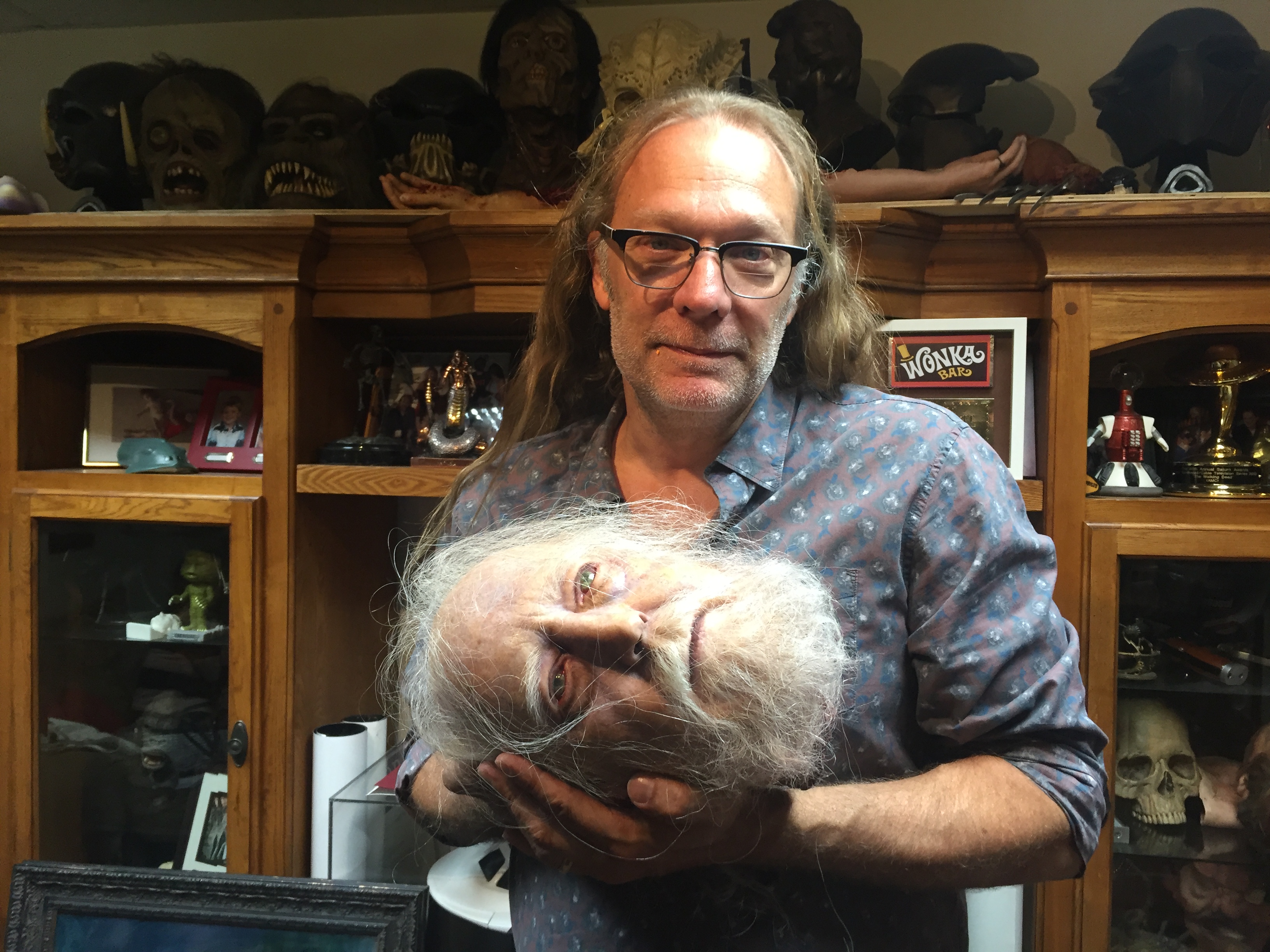 Special effects artist Greg Nicotero cradles the severed head of Hershel Greene, a character from AMC series 'The Walking Dead', as he poses for a photo at his studio KNB EFX in Chatsworth, California on June 8, 2016.  He is the God of Gore, the Sultan of Splatter, the Emperor of Entrails -- and the brains behind some of the most iconic blood and guts set-pieces in film history. If you've seen something in a violent movie that made the blood drain from your face, there's a good chance that Oscar-winning Greg Nicotero provided the special effects.  / AFP PHOTO / Frankie TAGGART