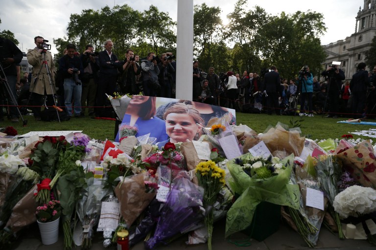 Members of the public gather at the heaped of tributes laid in remembrance of slain Labour MP Jo Cox (photo C) in Parliament square in front of the Houses of Parliament in London on June 17, 2016. Labour MP Jo Cox, a 41-year-old former aid worker also known for her advocacy for Syrian refugees, was killed on June 16, outside a library where she was supposed to meet constituents in Birstall in northern England, just a few miles (kilometres) from where she was born. / AFP PHOTO / DANIEL LEAL-OLIVAS