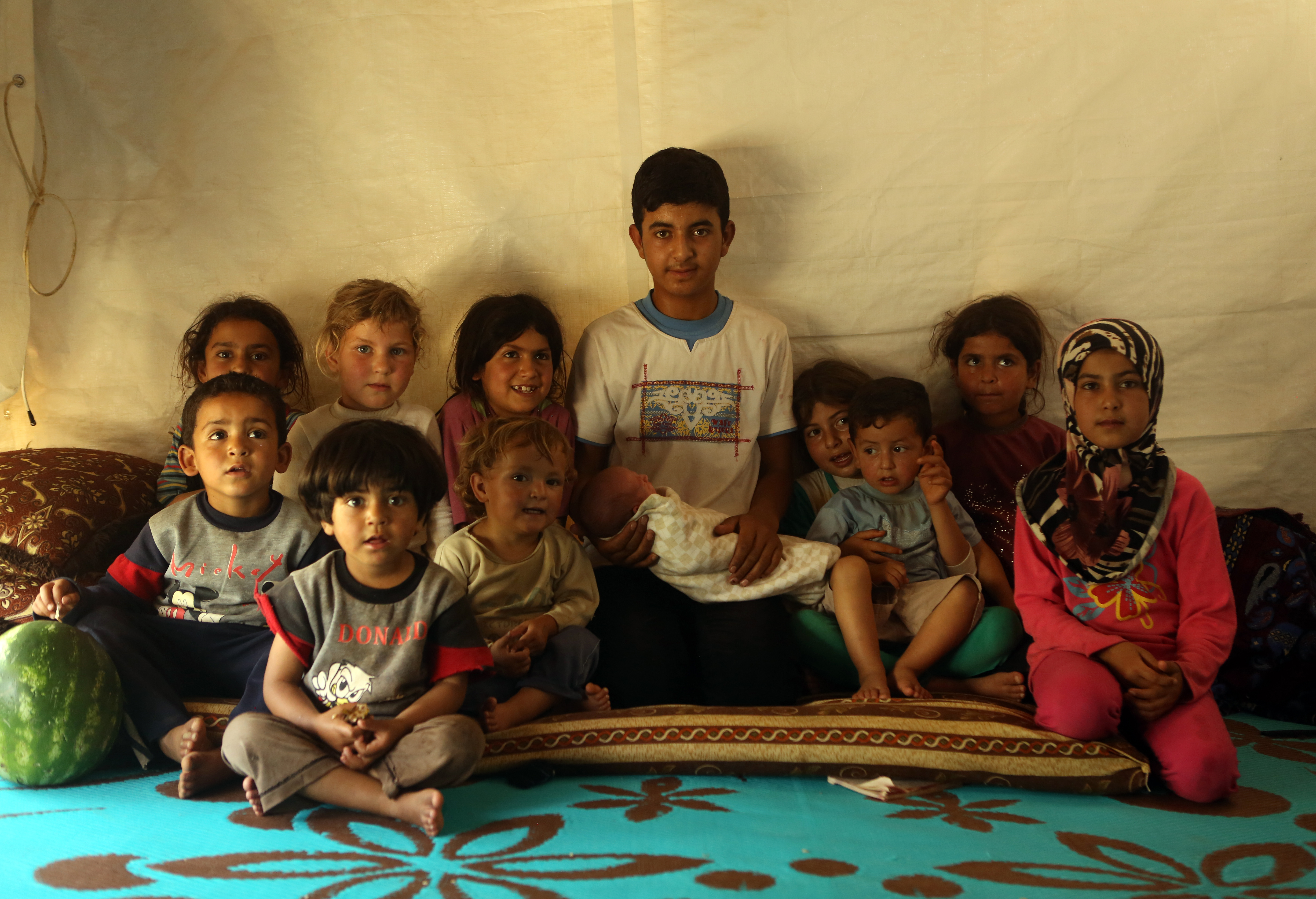 Syrian children part of a family of eighteen (15 children, two mothers and a father from Aleppo) pose for a picture in a makeshift tent in a Syrian refugee camp in the town of Kab Elias in Lebanon's Bekaa Valley on June 20, 2016. United Nations agencies marked World Refugee Day on June 19 in Syria, a country from which millions have fled a five-year civil war. Some refugees from other countries have decided to stay in Syria despite the devastating conflict. / AFP PHOTO / PATRICK BAZ