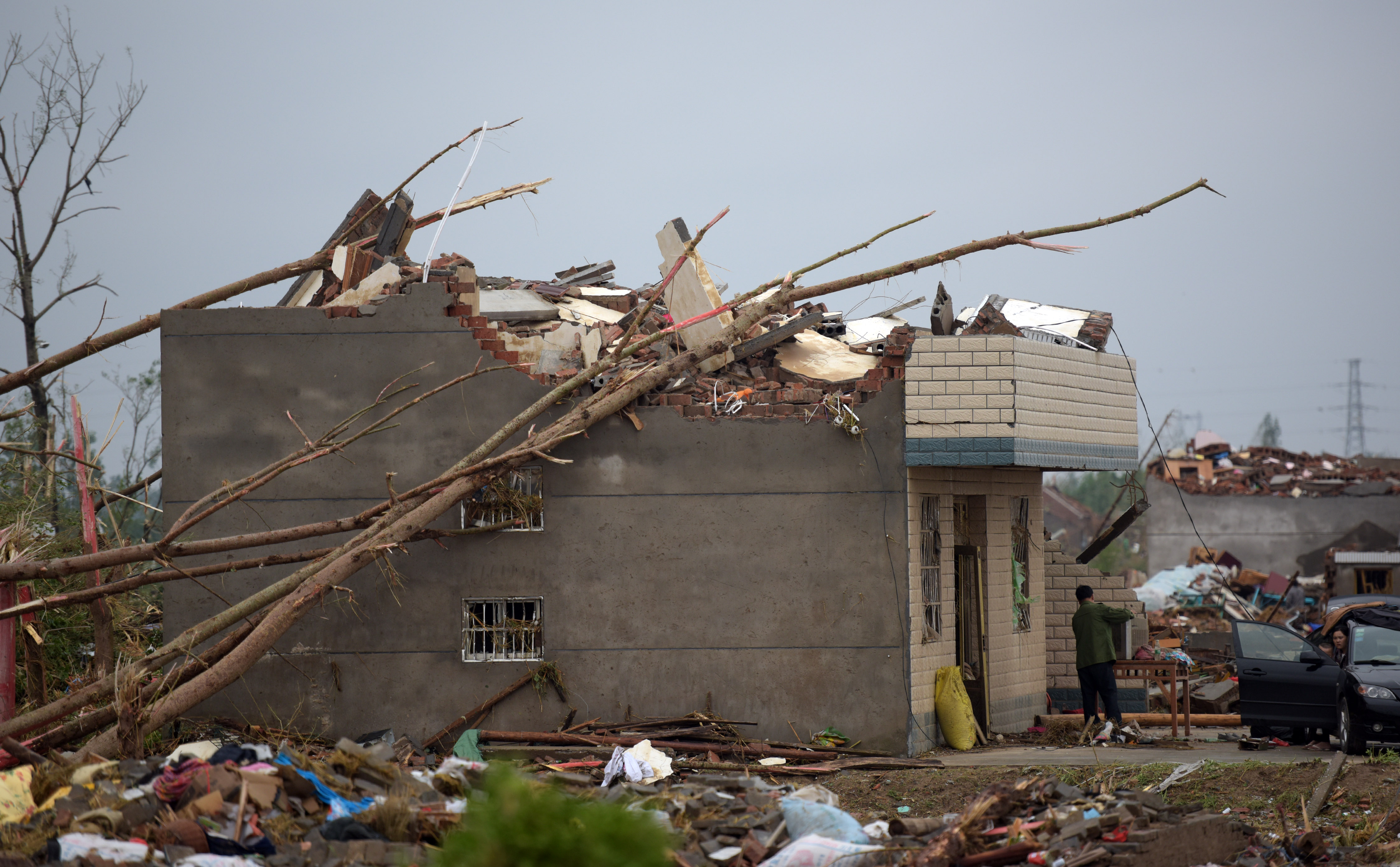 Residents walk in the rubble of destroyed houses after a tornado in Funing, in Yancheng, in China's Jiangsu province on June 24, 2016. Extreme weather, including hailstorms, heavy rain and a tornado, killed 78 and injured dozens in China's eastern Jiangsu province, the official Xinhua news agency reported on June 23.  / AFP PHOTO / JOHANNES EISELE