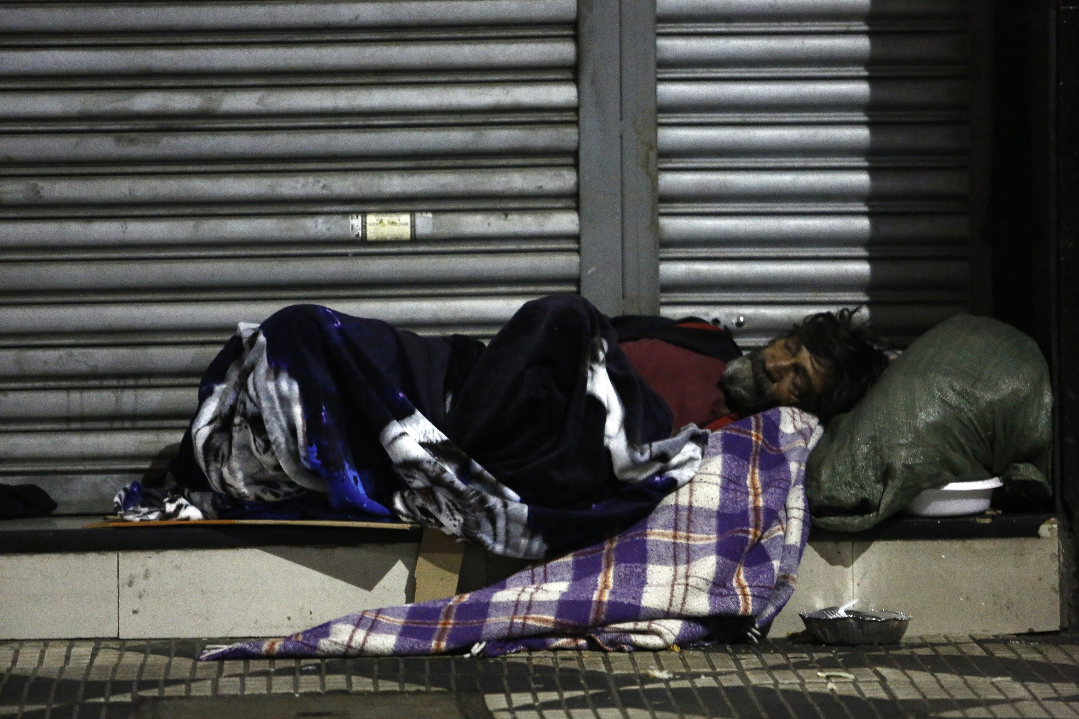 A homeless man spends the night on the street in downtown Sao Paulo, Brazil, on June 26, 2016. Earlier this month six homeless people died of cold in Sao Paulo, the richest city in Brazil, where some 16,000 homeless live on the streets. / AFP PHOTO / Miguel Schincariol / TO GO WITH AFP STORY BY ROSA SULLEIRO