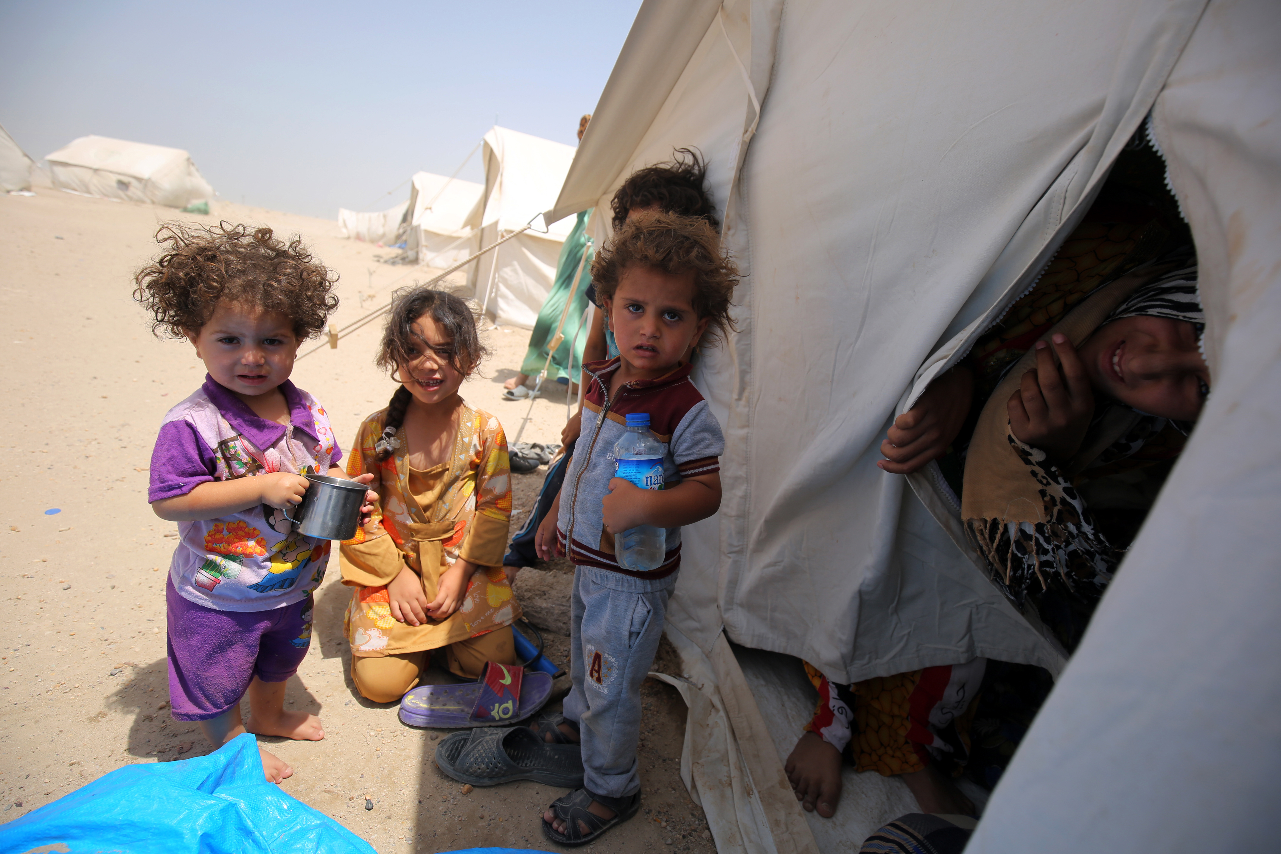 Iraqi children displaced from the city of Fallujah gather next to a tent at a newly opened camp where hundreds of displaced Iraqis are taking shelter in Amriyat al-Fallujah on June 27, 2016, south of Fallujah. Iraqi forces on June 26 wrapped up operations in Fallujah and declared the area free of jihadists from the Islamic State (IS) group after a month-long operation. The government said the destruction caused by the fighting was limited and vowed to do its utmost to allow the tens of thousands of displaced civilians to return to their homes.  / AFP PHOTO / AHMAD AL-RUBAYE