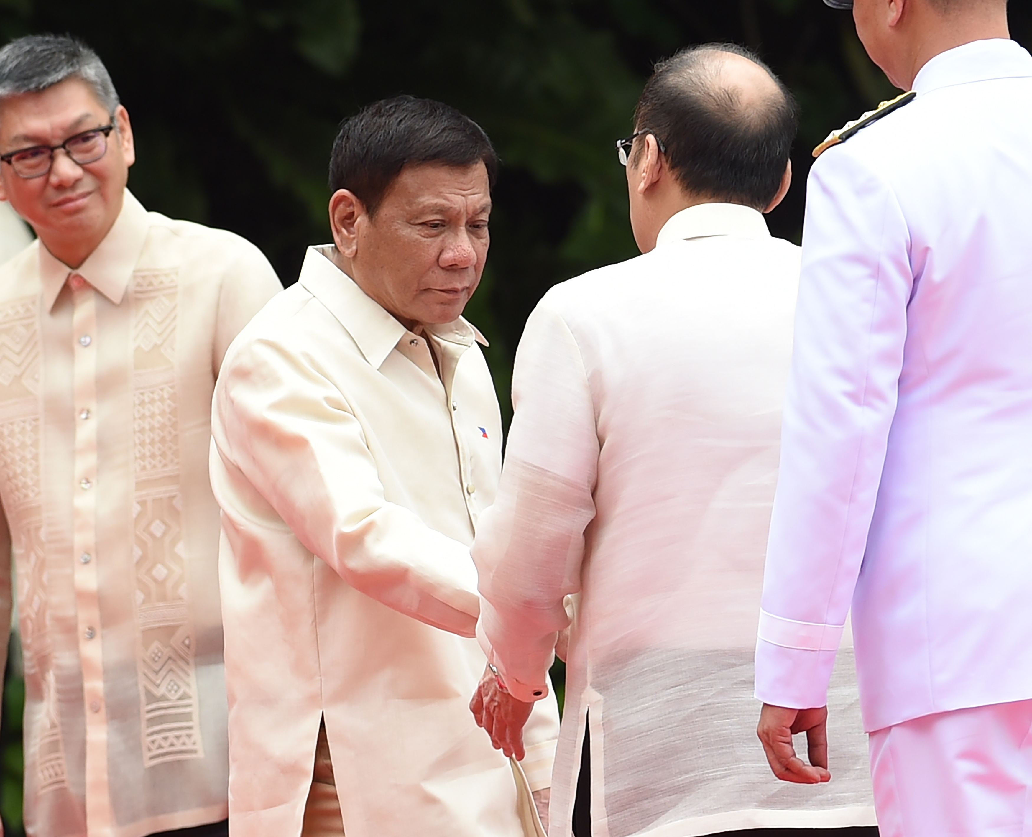 Outgoing Philippines President Benigno Aquino (2nd R) shakes hands with his successor Rodrigo Duterte (center 2nd L) during the departure ceremony for Aquino ahead of the swearing-in ceremony at Malacanang Palace in Manila on June 30, 2016.   Authoritarian firebrand Rodrigo Duterte takes office as Philippine president June 30, promising a ruthless and deeply controversial war on crime as the chief focus of his six-year term. / AFP PHOTO / TED ALJIBE