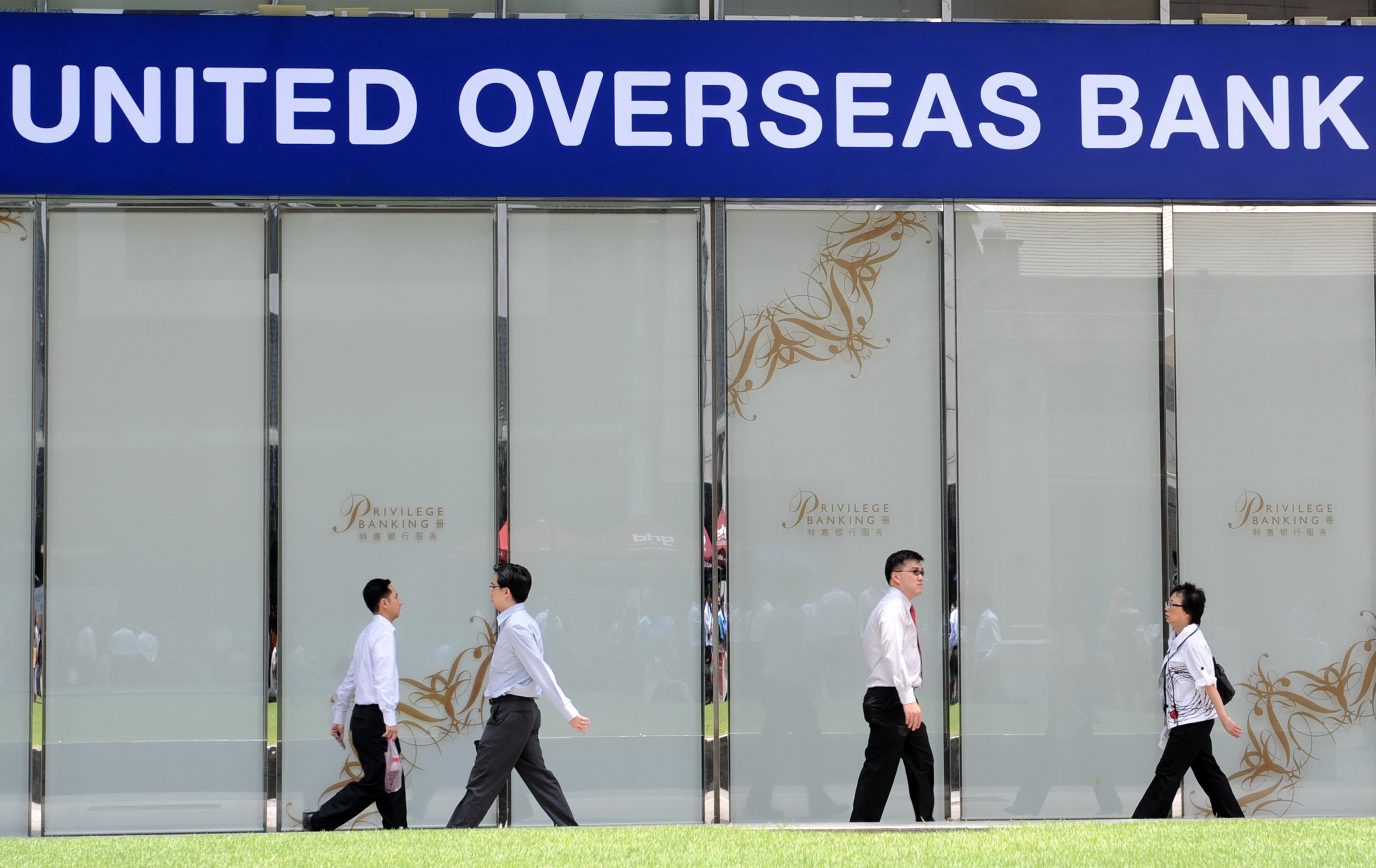 People walk past the local bank branch of the United Overseas Bank in Singapore on September 13, 2010. Banks will be required to lift their reserves substantially under "landmark" new rules drawn up September 12 by central bankers and regulators seeking to prevent a repeat of the recent financial crisis. The new regulations, called Basel III, would force banks to more than triple their current reserves and would be phased in from 2013, said a statement issued by the Bank for International Settlements in Zurich. AFP PHOTO / ROSLAN RAHMAN / AFP PHOTO / ROSLAN RAHMAN