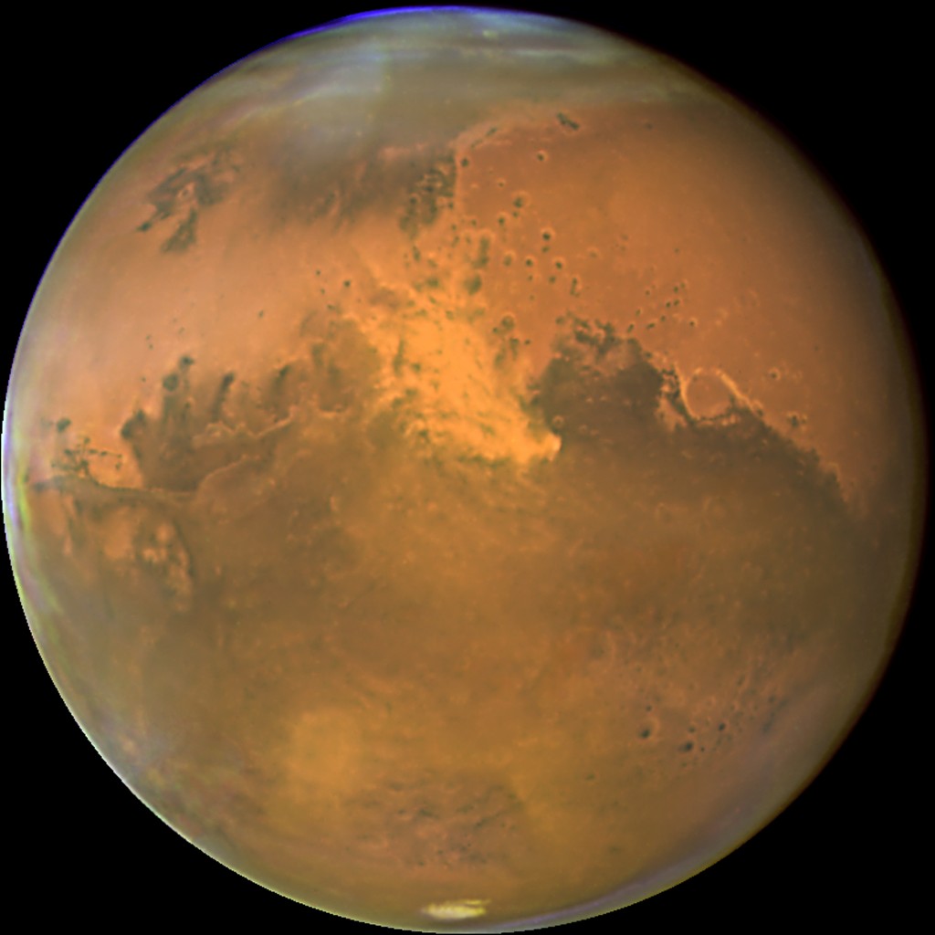 This NASA Hubble Space Telescope image released 03 November, 2005 shows Mars 28 October, within a day of its closest approach to Earth on the night of 29 October. The large regional dust storm(C) appears as the brighter, redder cloudy region in the middle of the planet's disk. This storm, which measures 930 miles (1500 km) has been churning in the planet's equatorial regions for several weeks now, and it is likely responsible for the reddish, dusty haze and other dust clouds seen across this hemisphere of the planet. Hubble's Advanced Camera for Surveys High Resolution Imager took this image when the red planet was 43 million miles (69 million km) from Earth. Mars won't be this close again to Earth until 2018. Mars is now in its warmest months, closest to the Sun in its orbit, resulting in a smaller than normal south polar ice cap which has largely sublimated with the approaching summer. AFP PHOTO/ NASA/ ESA / AFP PHOTO / NASA/ESA / HO