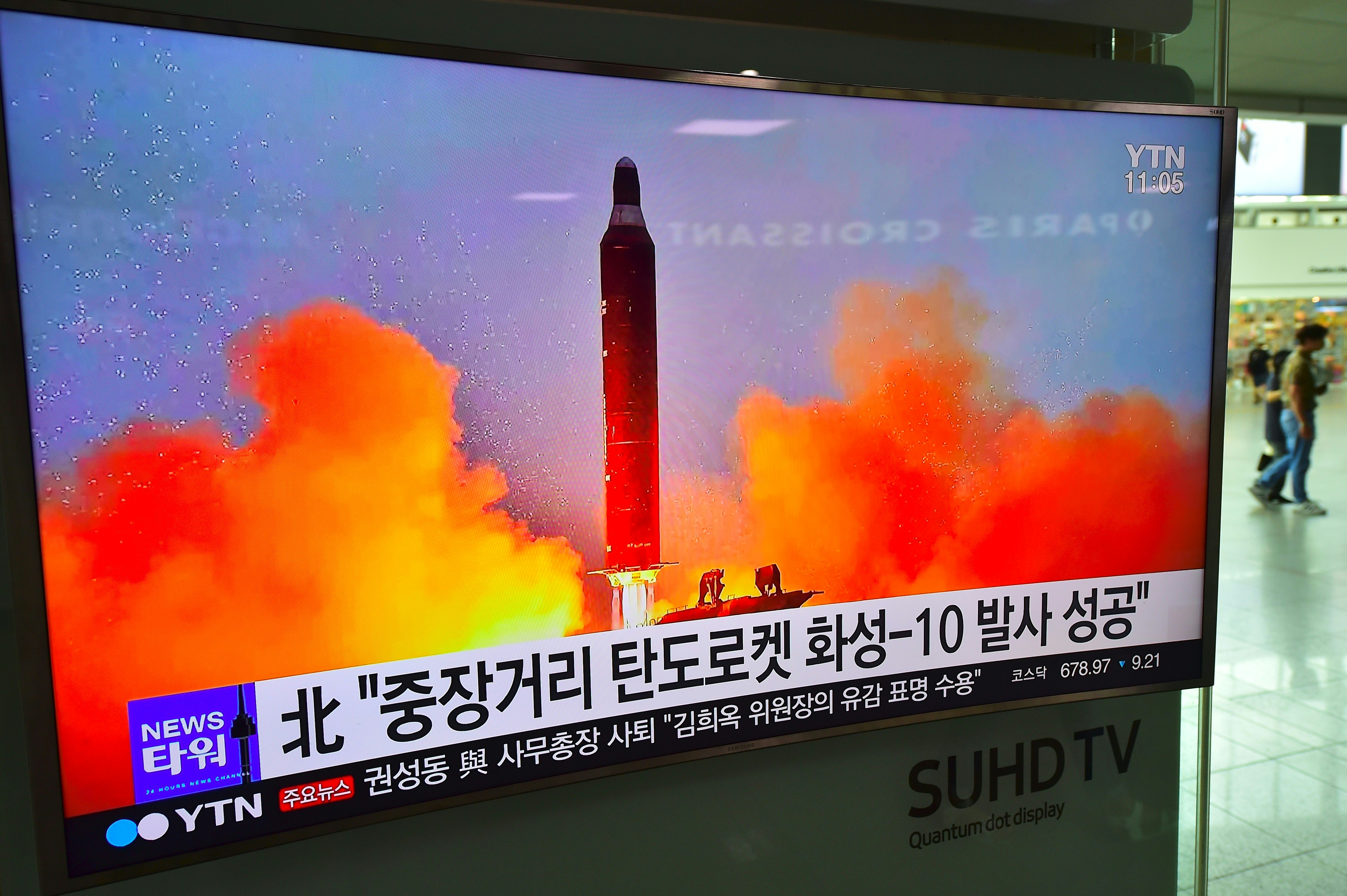 People walk past a television screen reporting news of North Korea's latest Musudan missile test, at a railway station in Seoul on June 23, 2016. North Korean leader Kim Jong-Un has hailed the successful test of a powerful new medium-range missile, saying it poses a direct threat to US military bases in the Pacific, state media reported on June 23. / AFP PHOTO / JUNG YEON-JE