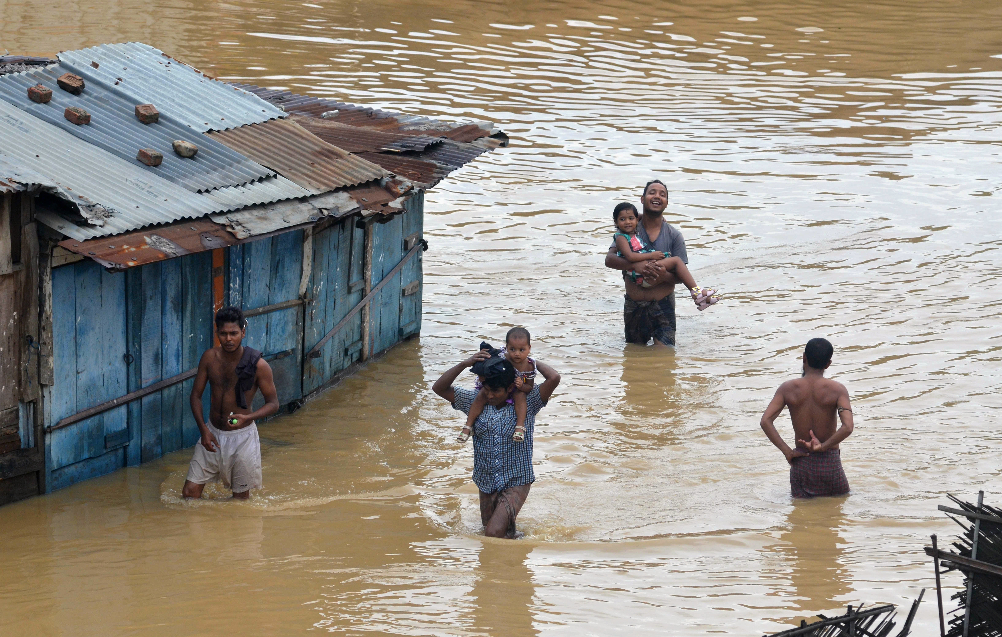 Residents wade through flood waters after heavy monsoon rain in Dimapur on June 28, 2016.  Thousands of people were flooded out of their homes in India's northeastern state of Nagaland following heavy monsoon rains. / AFP PHOTO / Caisii Mao