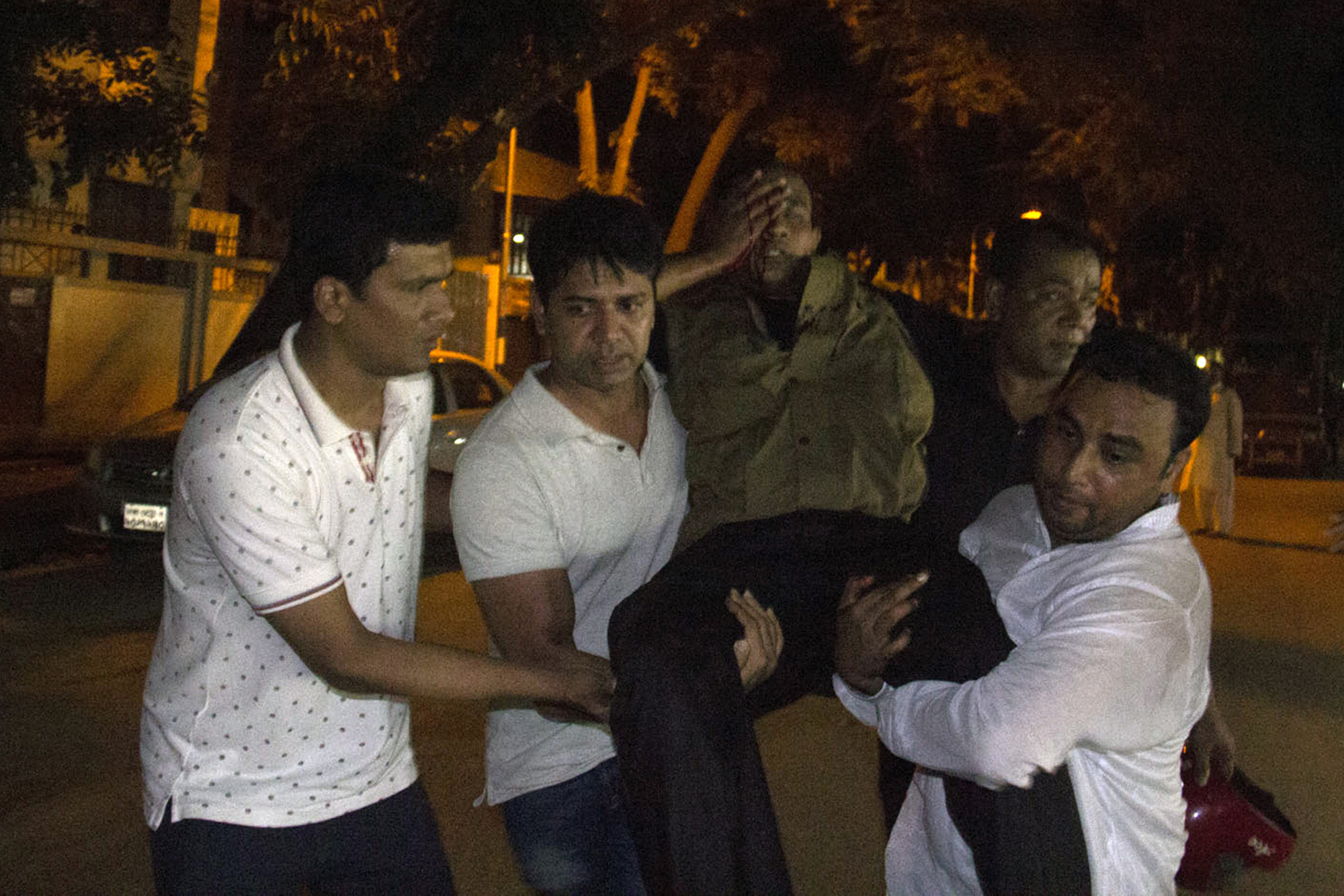 People carry an injured man near the Holey Artisan Bakery restaurant during an attack by unidentified gunmen in Dhaka's high-security diplomatic district on July 2, 2016. Gunmen stormed a crowded restaurant popular with foreigners in the Bangladeshi capital on July 1 night, apparently taking diners hostage and sparking a firefight with police in which at least two officers were killed, police and witnesses said. / AFP PHOTO / STR