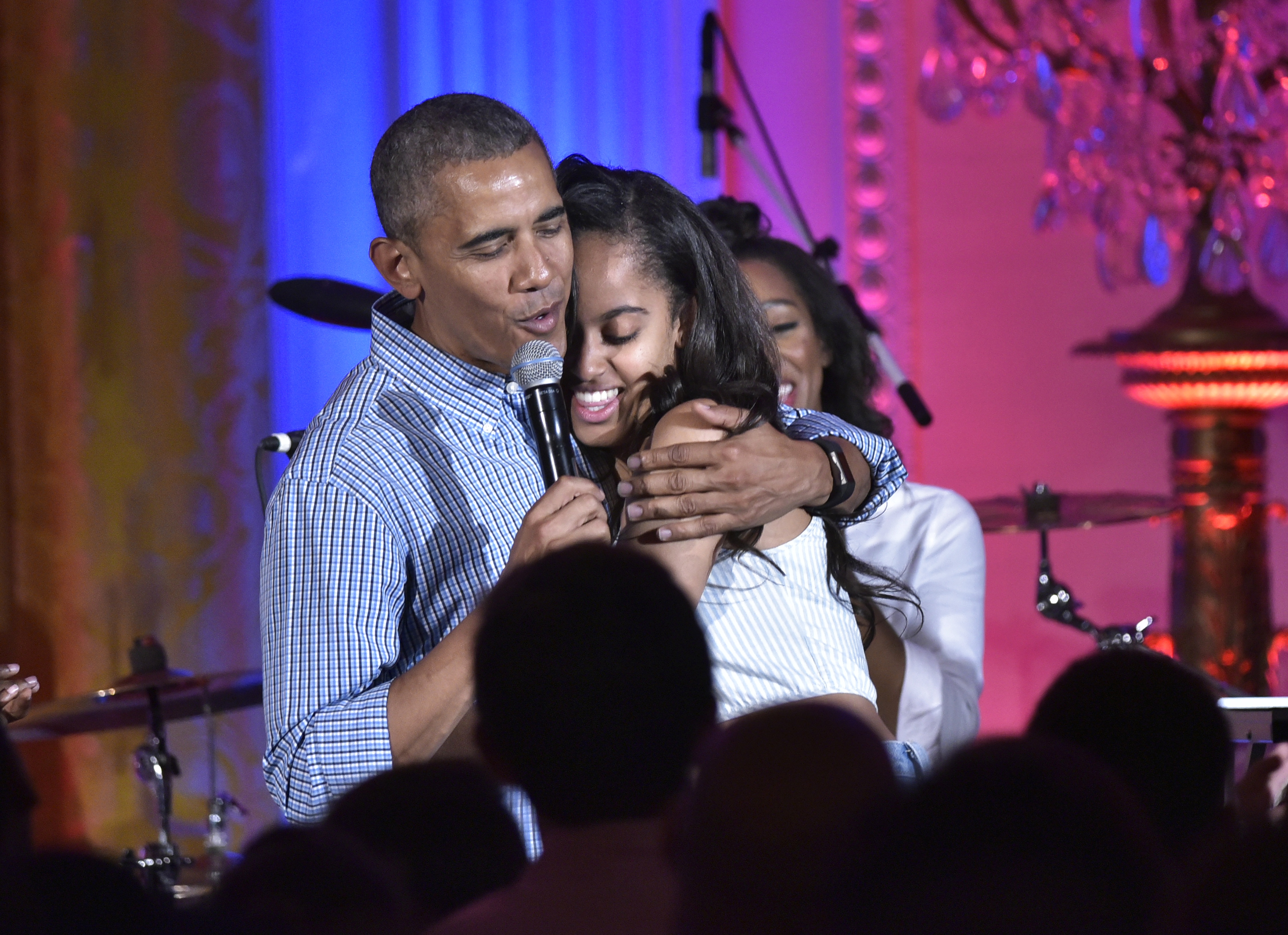 US President Barack Obama hugs his daughter Malia on her birthday during an Independence Day Celebration for military members and administration staff on July 4, 2016 in the East Room of the White House in Washington, DC. / AFP PHOTO / Mandel Ngan