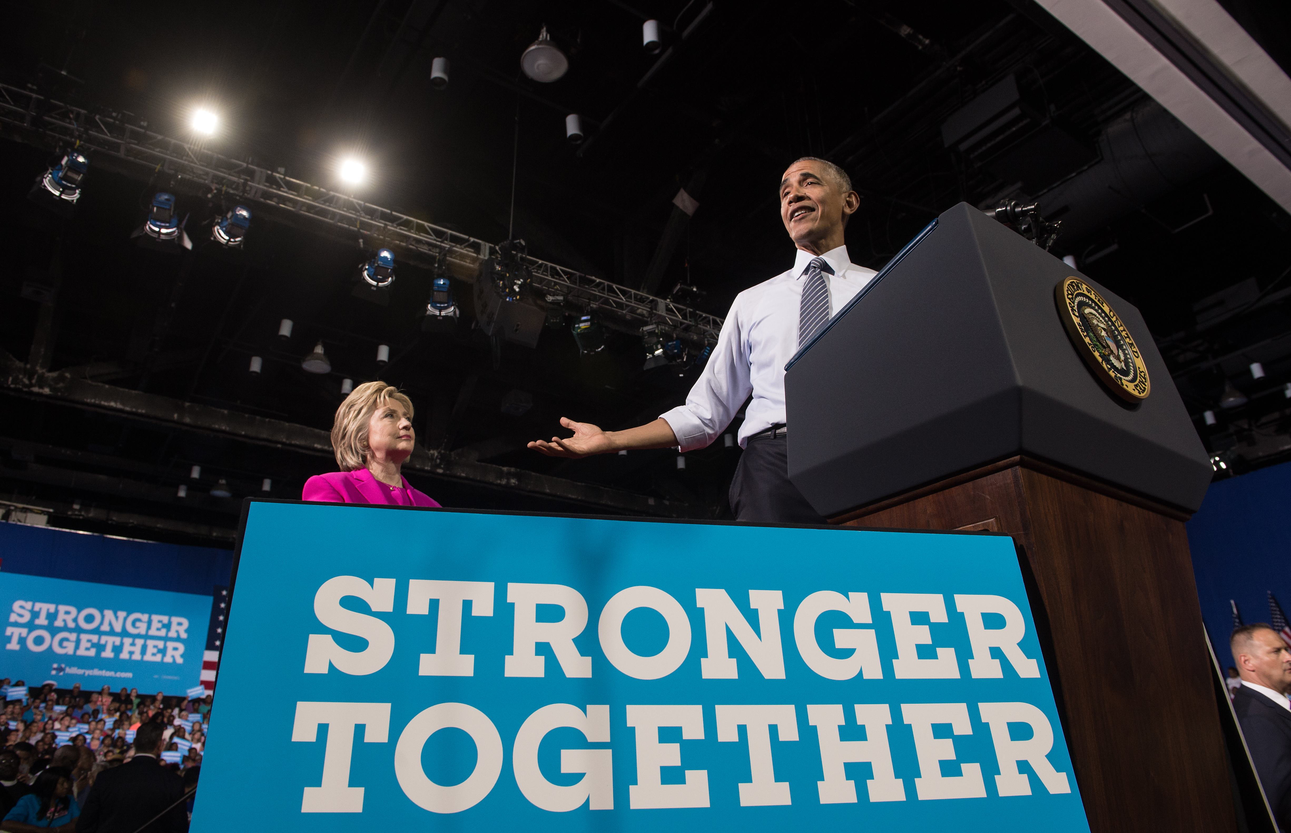US President Barack Obama speaks at a campaign event for Democratic presidential candidate Hillary Clinton (L) in Charlotte, North Carolina, on July 5, 2016. US President Barack Obama threw his full weight behind Hillary Clinton's bid to succeed him, extolling the experience and fighting spirit of his former secretary of state at their first joint campaign appearance. "I'm here today because I believe in Hillary Clinton," Obama told the rally in Charlotte, North Carolina. "There has never been any man or woman more qualified for this office." / AFP PHOTO / NICHOLAS KAMM