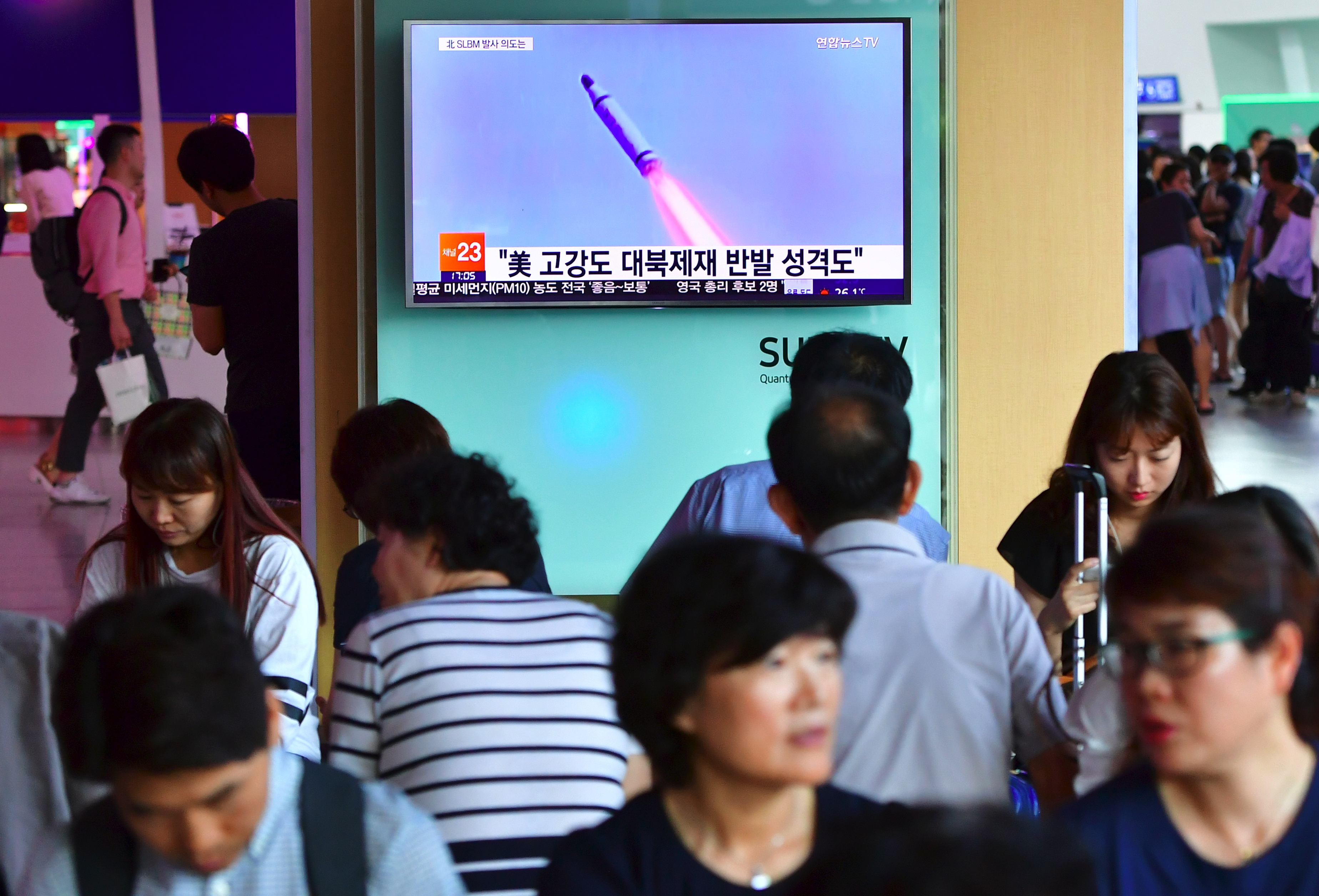 People watch a television news broadcast at a railway station in Seoul on July 9, 2016, showing file footage of a North Korean missile launch. North Korea on July 9 test-fired what appeared to be a submarine-launched ballistic missile (SLBM), Seoul's defence ministry said, a day after the US and South Korea decided to deploy an advanced missile defence system in the South. / AFP PHOTO / JUNG YEON-JE