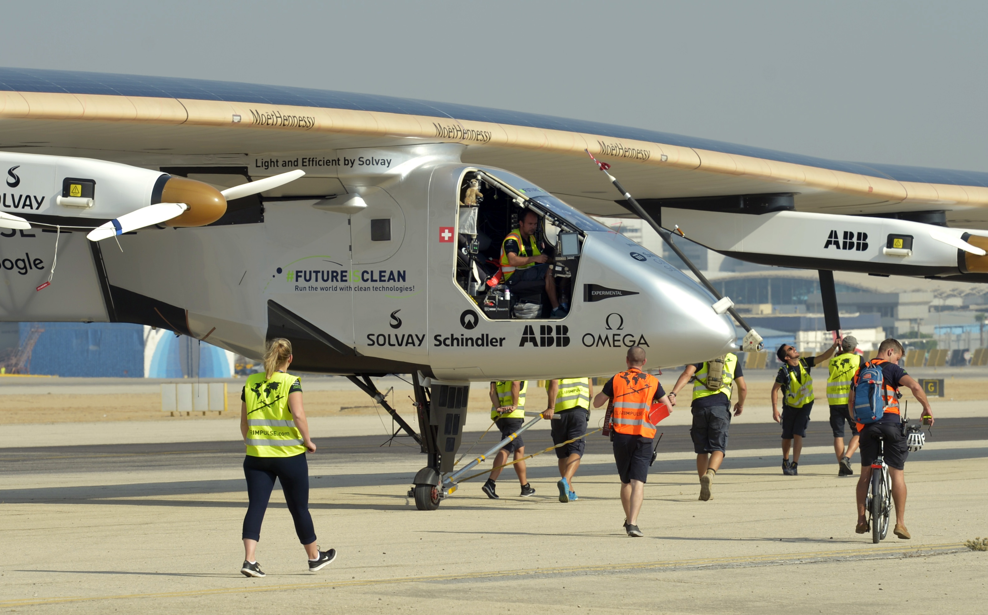 The ground crew of Solar Impulse 2, the solar powered plane, surrounds the aircraft after it landed at Cairo International Airport on July 13, 2016, for the penultimate stage of its world tour. The round-the-world solar flight is estimated to take some 500 flight hours and cover 35,000 km with Swiss founders and pilots, Bertrand Piccard and Andre Borschberg landing every few days to switch between piloting and hosting public events.  / AFP PHOTO / KHALED DESOUKI