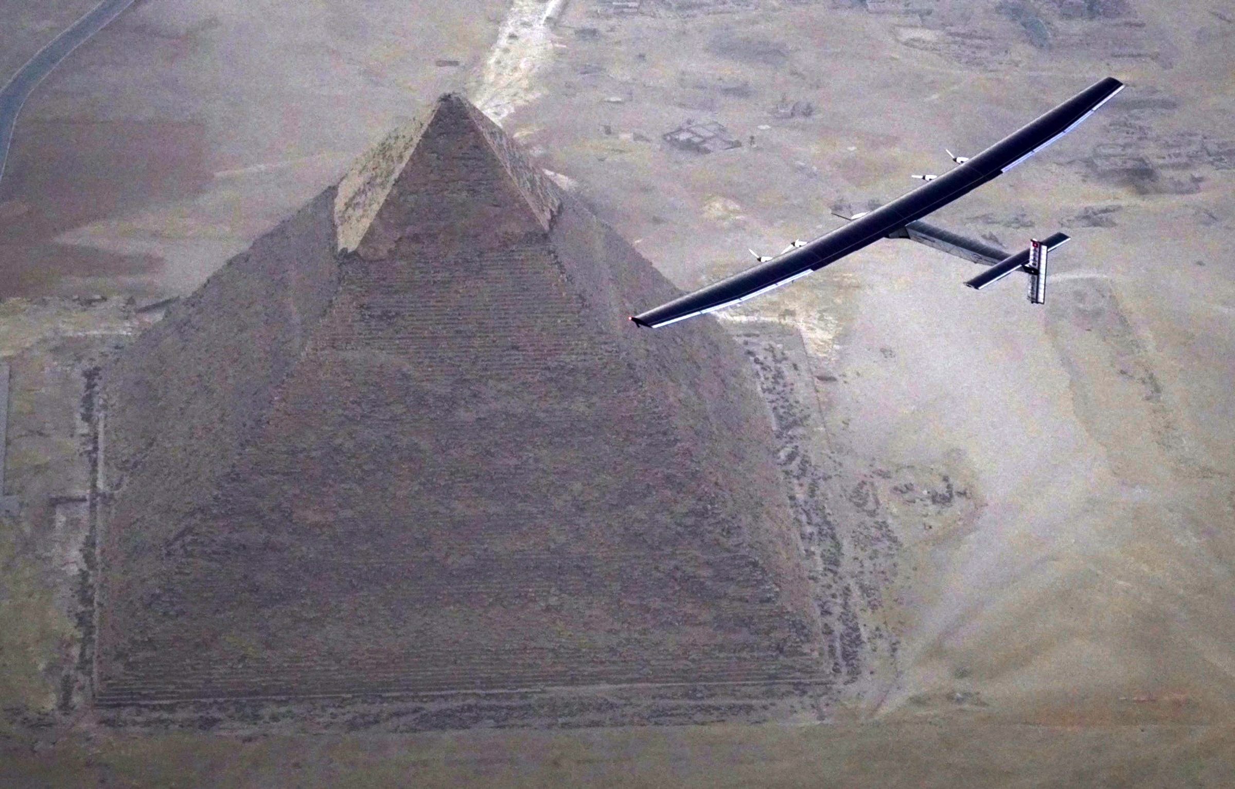 Solar Impulse 2, the solar powered plane, piloted by Swiss pioneer André Borschberg, is seen during the flyover of the pyramids of Giza on July 13, 2016 prior to landing in Cairo, Egypt. The 16th leg of the round-the-world-trip from Seville in Spain covered a distance of 3,700 kilometers and took almost 49 hours. The Solar Impulse 2 landed in Cairo on July 13, 2016  for the penultimate stop in the solar-powered plane's world tour, two days after setting off from Spain. The 16th leg of the round-the-world-trip from Seville in Spain covered a distance of 3,700 kilometers and took almost 49 hours. / AFP PHOTO / Solar Impulse 2 / Jean Revillard / XGTY  == RESTRICTED TO EDITORIAL USE  / MANDATORY CREDIT:  "AFP PHOTO / SOLAR IMPULSE 2 / Jean Revillard" / NO MARKETING / NO ADVERTISING CAMPAIGNS /  DISTRIBUTED AS A SERVICE TO CLIENTS  ==