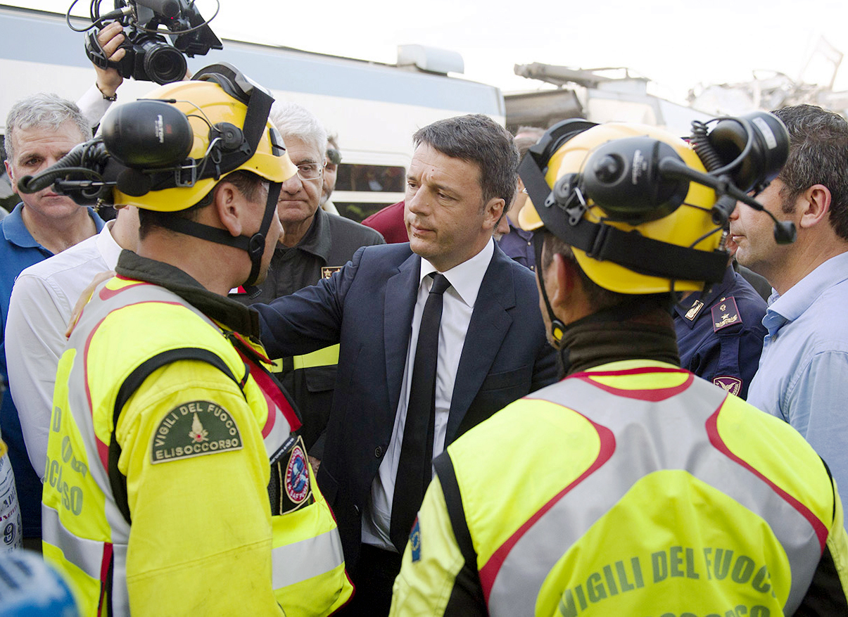 This handout picture released by the Italian Prime Minister press office on July 12, 2016 shows Italy's Prime Minister Matteo Renzi (C) talking with firefighters at the site of a collision between two trains, near Corato, in the southern Italian region of Puglia. At least 27 people were killed in a head-on collision between two passenger trains, in one of the country's worst rail accidents in recent years. / AFP PHOTO / Palazzo Chigi press office / Tiberio Barchielli