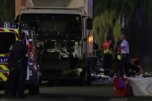 EDITORS NOTE: Graphic content / Police officers stand near a van, with its windscreen riddled with bullets, that ploughed into a crowd leaving a fireworks display in the French Riviera town of Nice on July 14, 2016. At least 60 people were killed when a truck ploughed into a crowd watching a Bastille Day fireworks display in the southern French resort of Nice, prosecutors said early on July 15. Nice prosecutor Jean-Michel Pretre said the truck drove two kilometres (1.3 miles) through a large crowd that was watching the fireworks.  / AFP PHOTO / VALERY HACHE