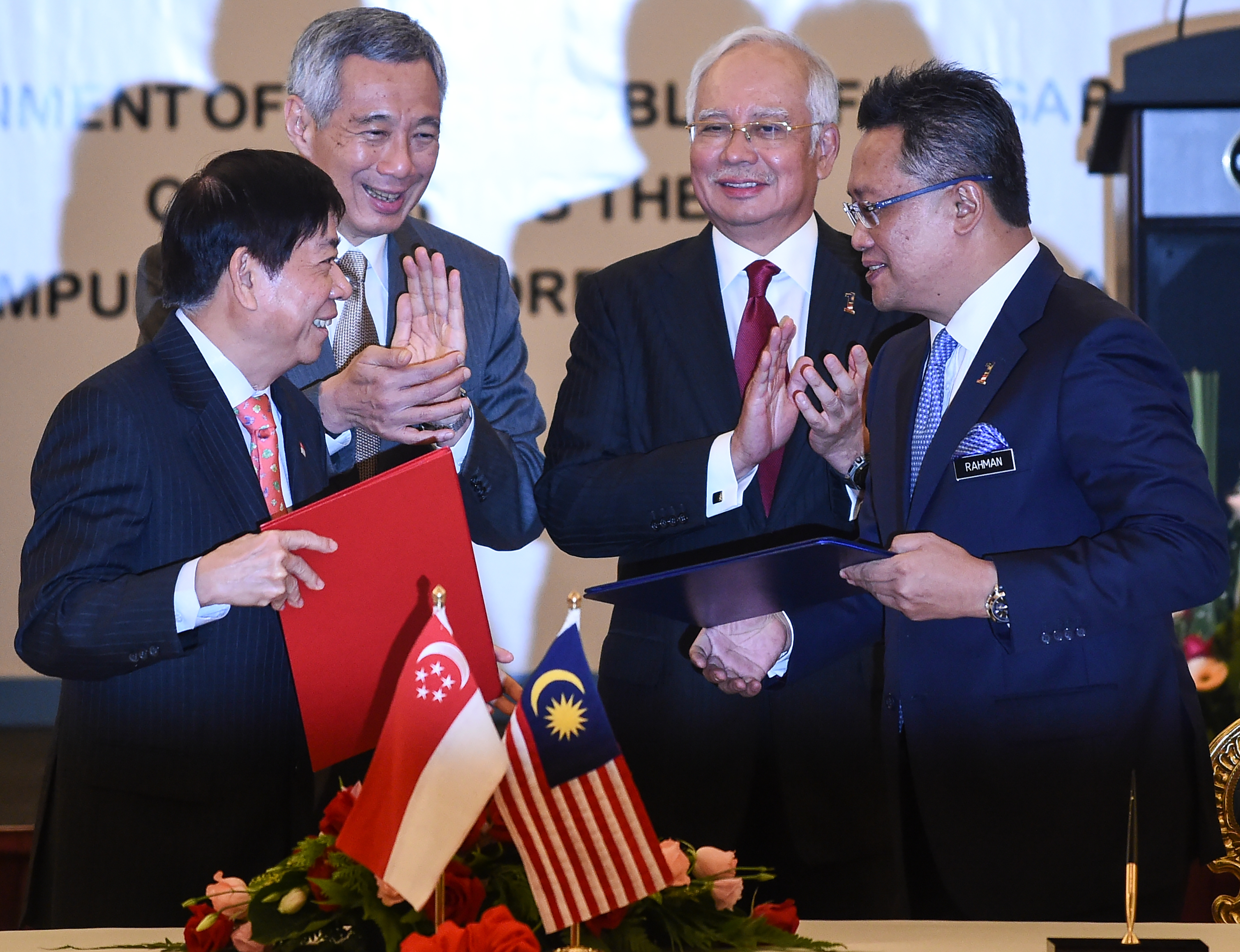 Malaysia's Minister in the Prime Minister's Department Abdul Rahman Dahlan (R) and Singapore's Transport Minister Khaw Boon Wan (L) exchange documents as Malaysia's Prime Minister Najib Razak (2nd R) and Singapore's Prime Minister Lee Hsien Loong (2nd L) applaud during the signing of a memorandum of understanding between the two goverments concerning the Kuala Lumpur-Singapore high-speed rail link, at Najib's official residence in Putrajaya, outside Kuala Lumpur on July 19, 2016. Malaysia and Singapore signed an agreement on July 19 to build an ambitious high-speed rail link touted as a first for Southeast Asia that will knit the historically fractious neighbours more closely together. / AFP PHOTO / MOHD RASFAN