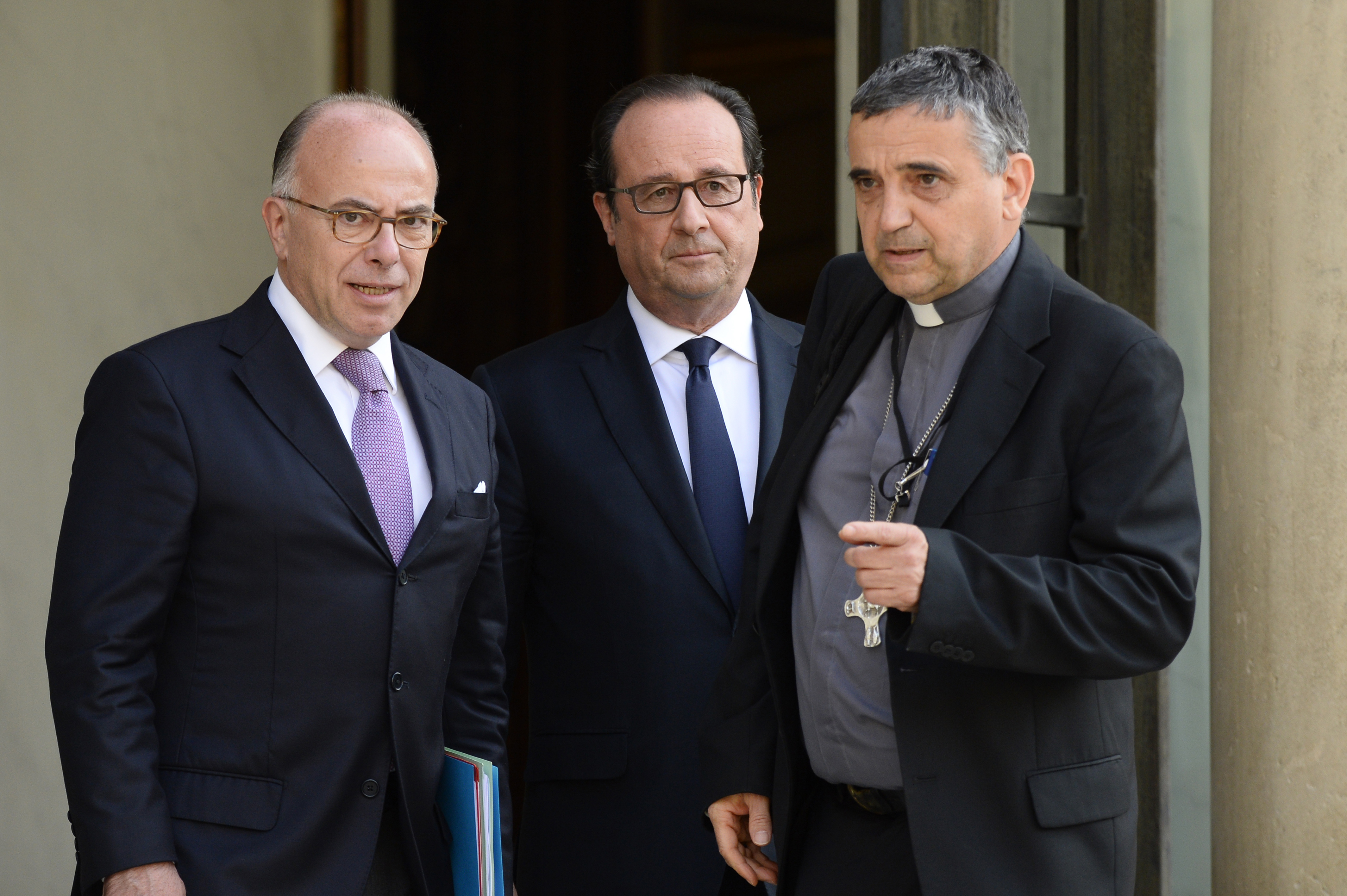 Archbishop of Rouen Dominique Lebrun (R) leaves after a meeting with French President Francois Hollande (C) and French Interior Minister Bernard Cazeneuve (L) on July 26, 2016 at the Elysee Palace in Paris, after a priest was killed earlier today in the Normandy city of Saint-Etienne-du-Rouvray.  Francois Hollande said that two men who attacked a church and slit the throat of a priest had "claimed to be from Daesh", using the Arabic name for the Islamic State group. Police said they killed two hostage-takers in the attack in the Normandy town of Saint-Etienne-du-Rouvray, 125 kilometres (77 miles) north of Paris. / AFP PHOTO / BERTRAND GUAY