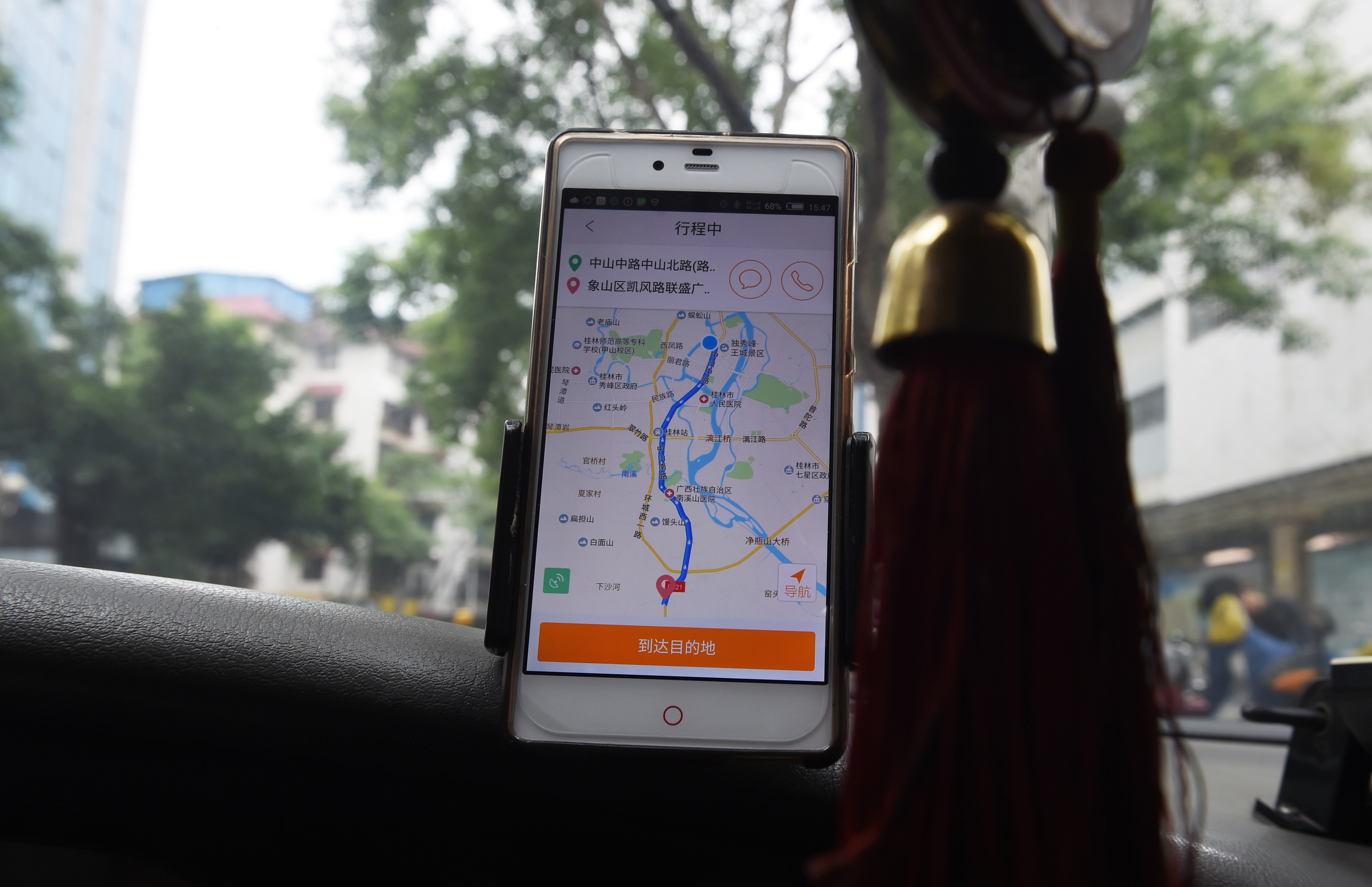 A taxi driver uses the Didi Chuxing app while driving along a street in Guilin, in China's southern Guangxi region on May 13, 2016. Apple has invested 1 billion USD in Chinese ride hailing app Didi Chuxing, the Beijing company said on May 13, as it vies with bitter US-based rival Uber for market share in China. / AFP PHOTO / GREG BAKER