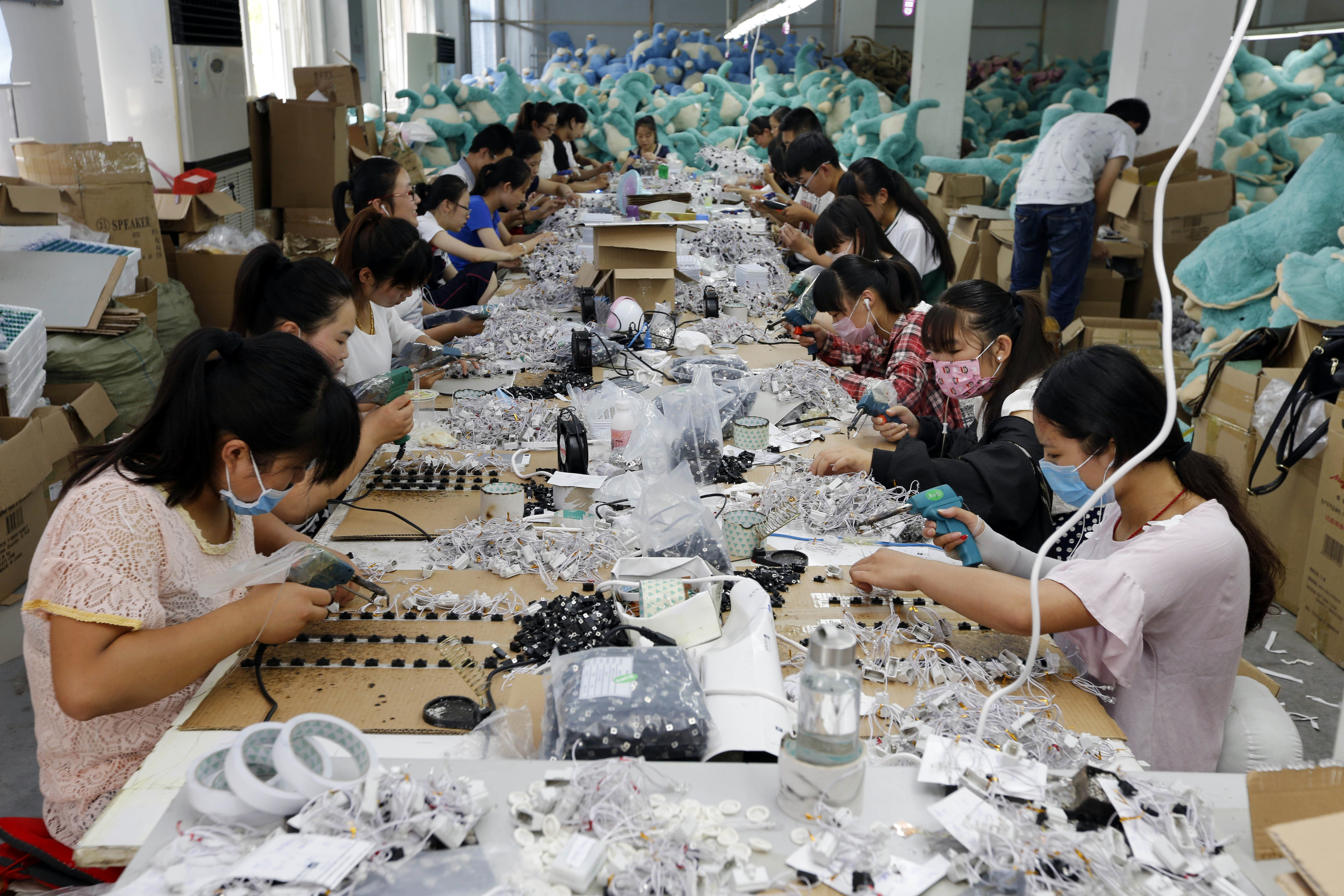 This photo taken on July 12, 2016 shows workers in the process of making soft toys at a toy factory in Lianyungang, in eastern China's Jiangsu province. China's growth slipped to a new seven-year low of 6.6 percent in the second quarter, according to an AFP survey, despite government efforts to spur activity in the world's second-largest economy. / AFP PHOTO / STR / China OUT