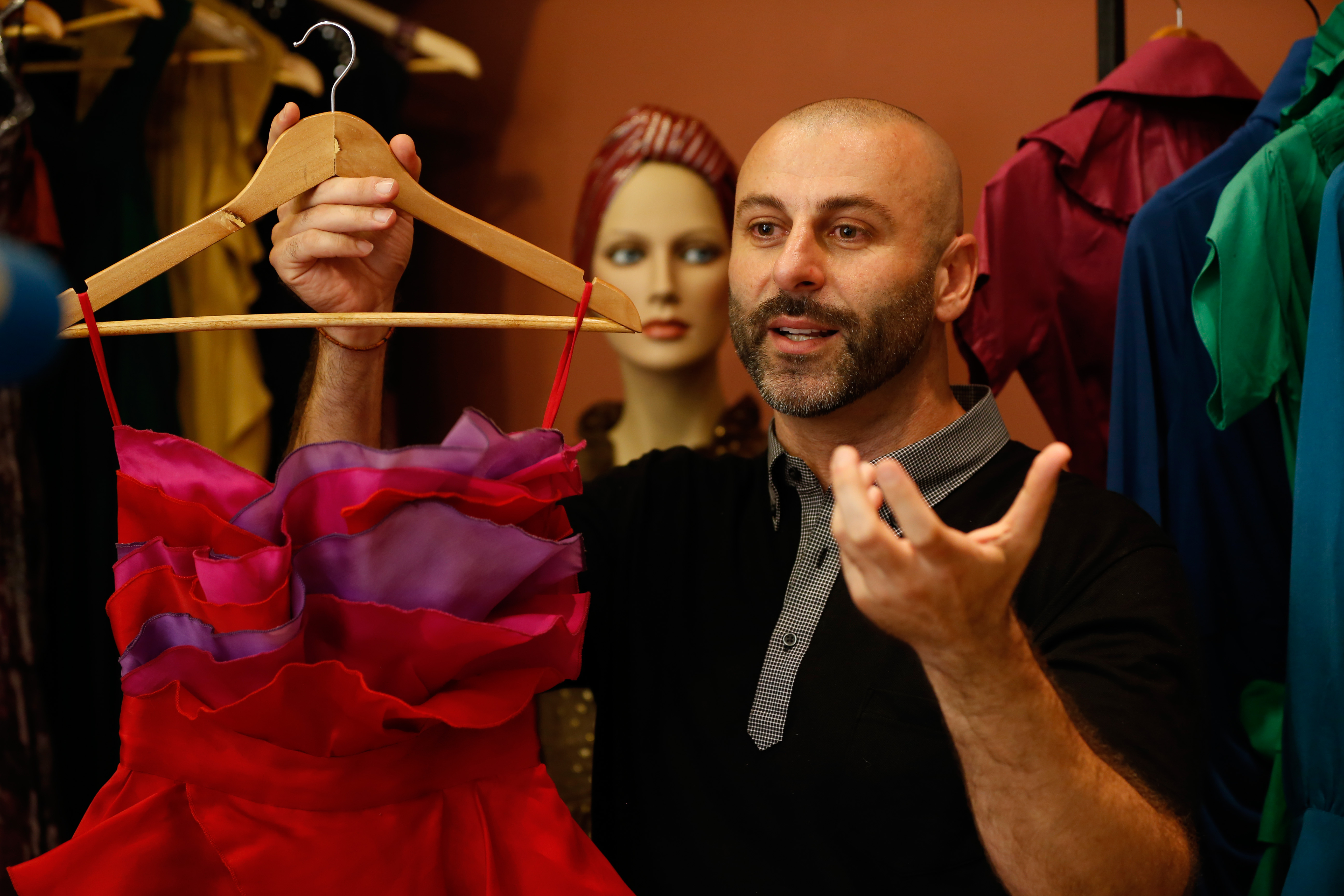 Palestinian American fashion designer Rami Kashou shows one of his designs, during a fitting session, at a pop-up  shop in the West Bank city of Ramallah on July 27, 2016.  The world-renouned designer who has been away from his native city for several years, showed his designs to Palestinian women in the Ramallah shop for 3 days. Kashou's clients include Jordan's queen Rania, the top model Heidi Klum and public figure Kim Kardashian.  / AFP PHOTO / ABBAS MOMANI
