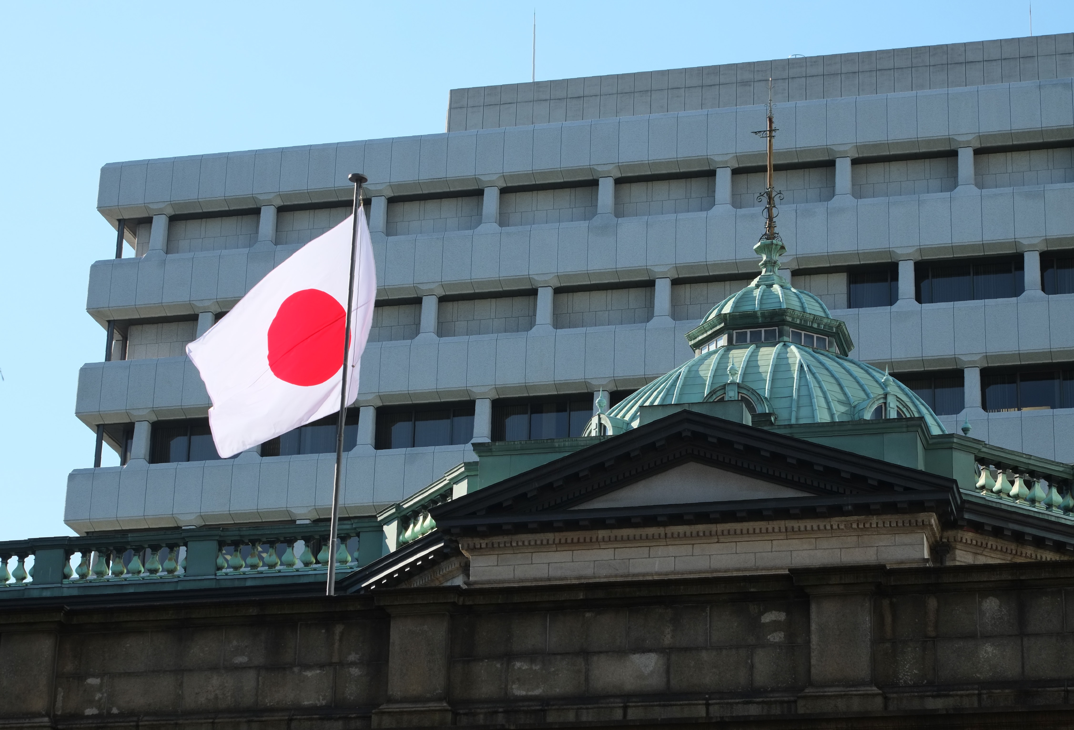The Japanese national flag is seen on the Bank of Japan headquarters in Tokyo on July 29, 2016. Tokyo shares rose on July 29 with lenders boosted by the Bank of Japan's decision not to cut interest rates further into negative territory, which could have dented their profits. / AFP PHOTO / KAZUHIRO NOGI