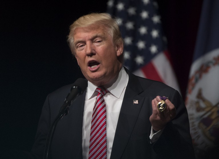 Republican presidential nominee Donald Trump holds a purple heart medal given to him by Lt. Col. Louis Dorfman during a campaign event at Briar Woods High School August 2, 2016, in Ashburn, Virginia. / AFP PHOTO / MOLLY RILEY