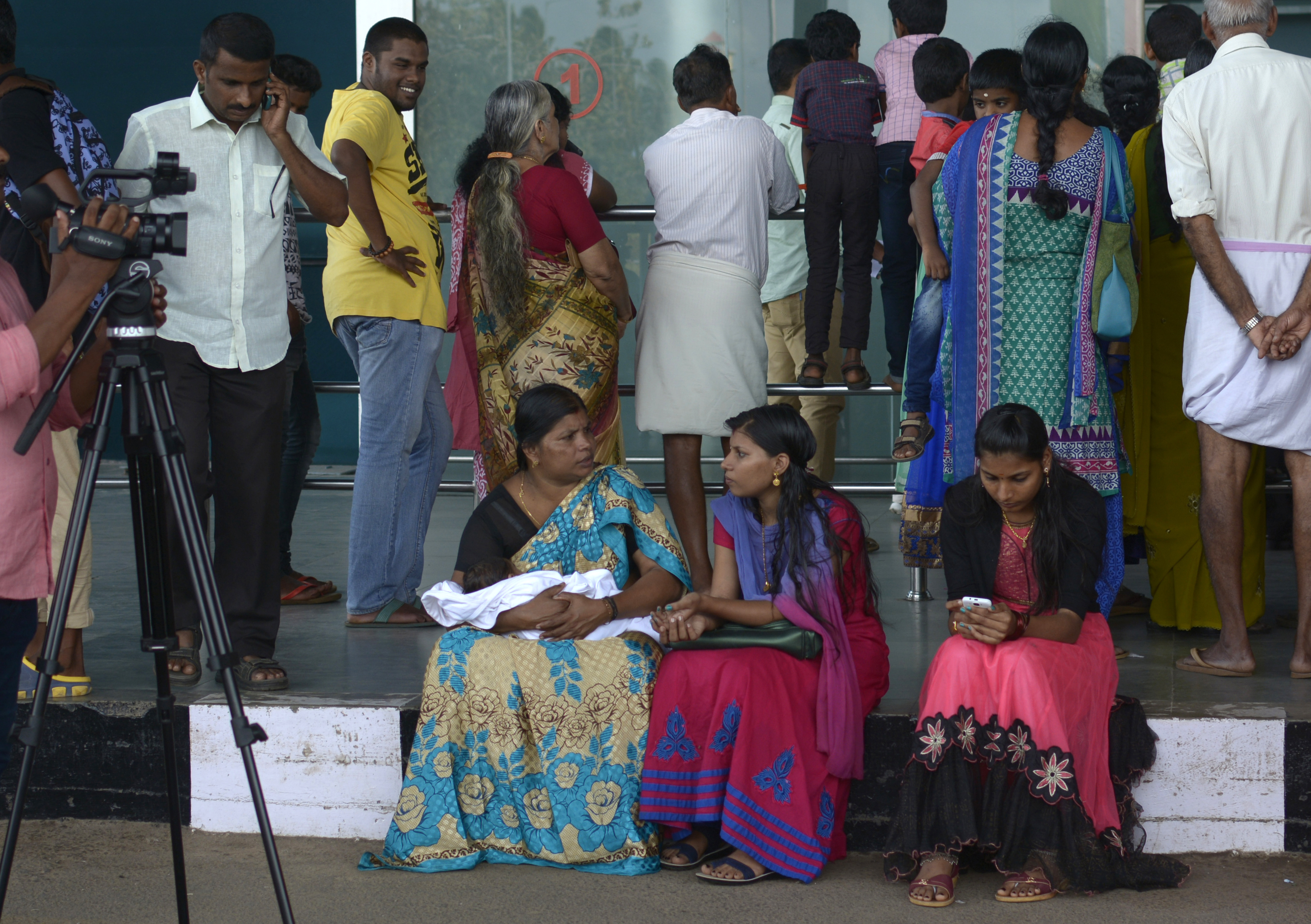 Passengers and relatives wait for news after hearing that the Emirates flight EK521 travelling from Thiruvananthapuram to Dubai crash landed at Dubai International Airport, at the departures terminal of Thiruvananthapuram International Airport on August 3, 2016. An Emirates plane with 300 people on board crash-landed and caught fire in Dubai, shutting down the busy airport, but the authorities said all the passengers were evacuated safely. / AFP PHOTO / STRINGER