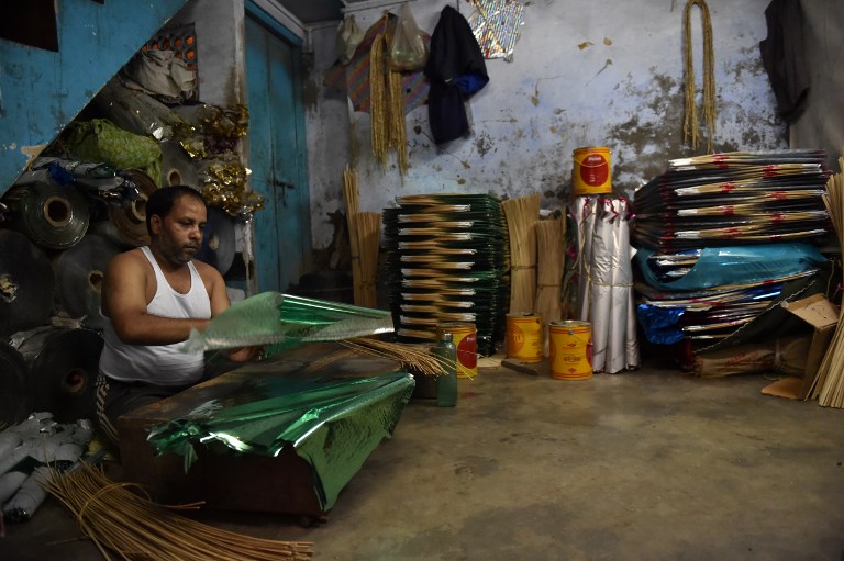 An Indian kite maker prepares kites at his workshop in the old quarters of New Delhi on August 4, 2016. / AFP PHOTO / SAJJAD HUSSAIN