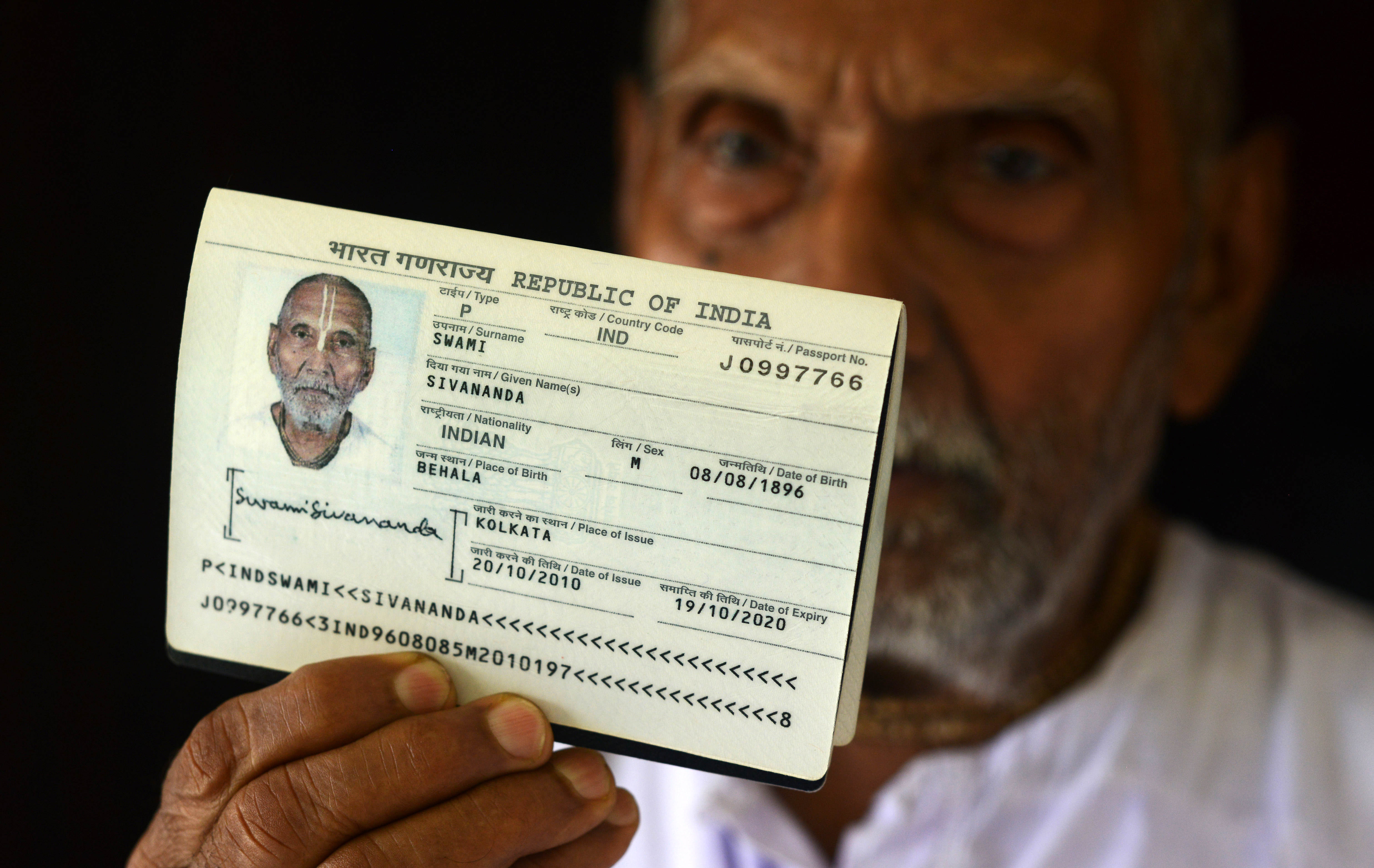 In this photograph taken on August 2, 2016, Indian monk Swami Sivananda, who claims to be 120 years old, holds up his passport in the house of one of his followers in Kolkata.   An Indian monk who claims to be the oldest man to have ever lived at 120 years, says he owes his longevity to daily yoga and a life without sex or spices. Born on August 8, 1896, according to his passport, Hindu monk Swami Sivananda's life has spanned three centuries. He is now applying to Guinness World Records to stake his claim to the distinction.  / AFP PHOTO / Dibyangshu SARKAR / TO GO WITH AFP STORY:  ' India-Lifestyle-Oldest-Man' Feature by Dibyangshu SARKAR