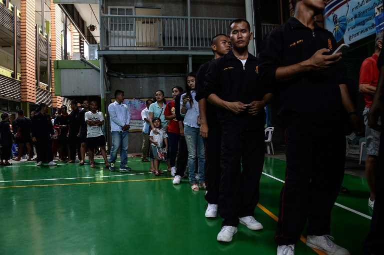 People queue before casting their ballots at a local polling station during the constitutional referendum in Bangkok on August 7, 2016. Thailand began voting on a junta-crafted constitution August 7 in a referendum where independent campaigning and open debate has been banned, as opponents warn the document will perpetuate military power. / AFP PHOTO / LILLIAN SUWANRUMPHA