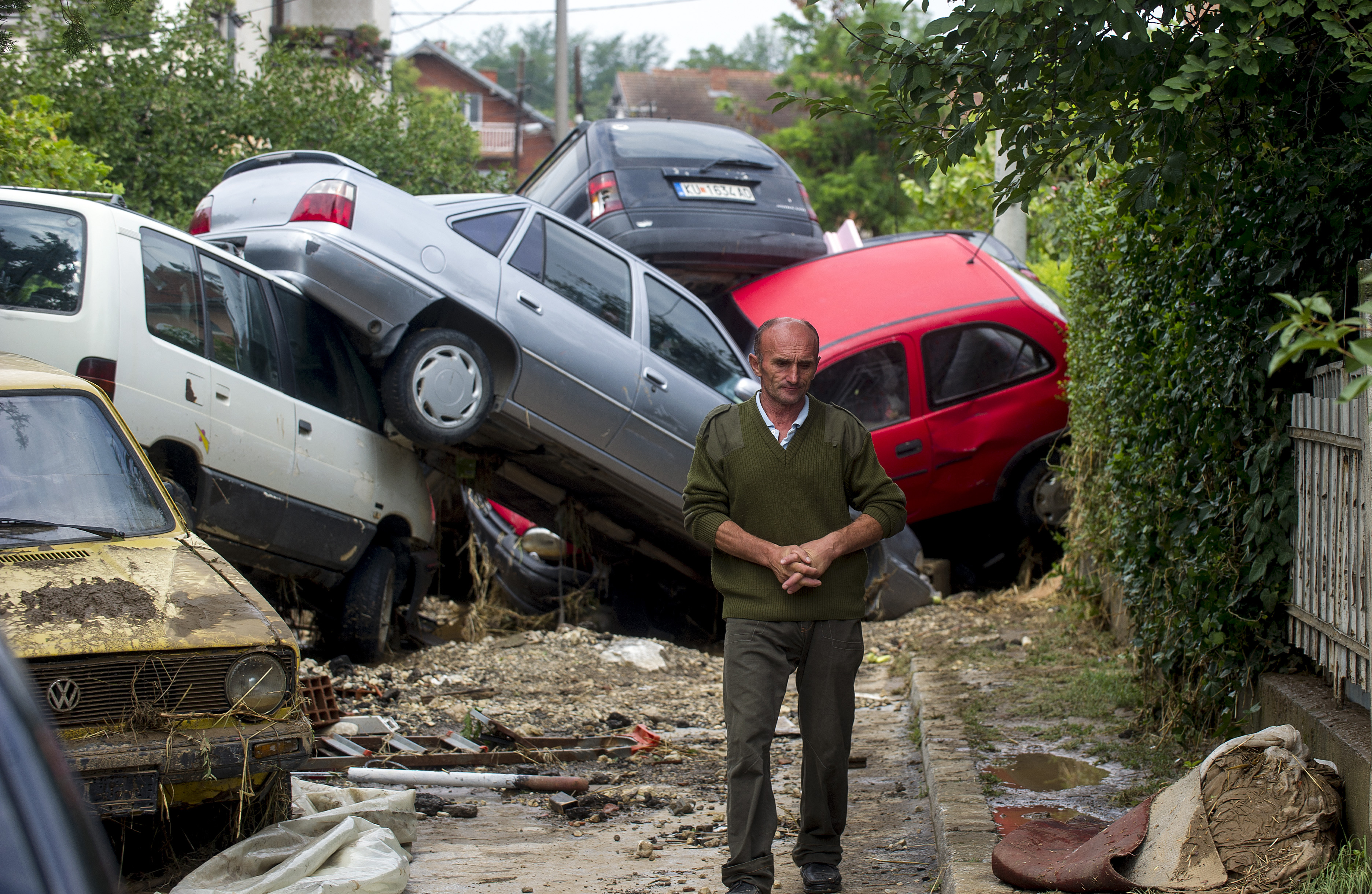 A man passes damaged vehicles in the village of Stajkovci, near Skopje, on August 7, 2016, following overnight torrential rains and fierce storms. Fierce storms packing strong winds and torrential rains overnight killed at least 20 people in Macedonia's capital of Skopje, the health minister said August 7. The freak weather included winds blowing at more than 70 kilometres (43 miles) an hour and resulted in flash floods and landslides, with cars swept away by the violent torrents. / AFP PHOTO / Robert ATANASOVSKI
