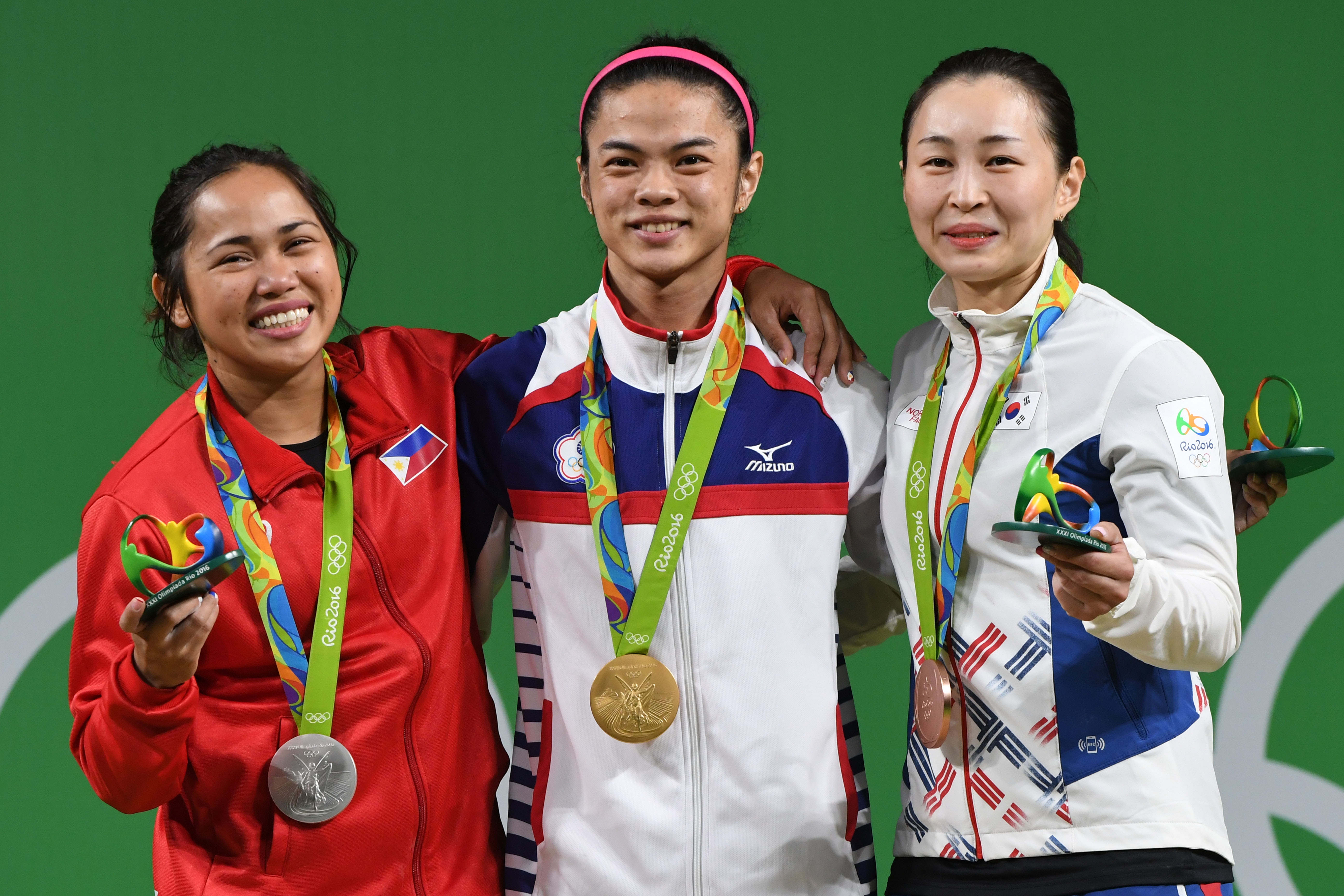 Tawain's gold medallist Hsu Shu-Ching (C), Philippines' silver medallist Hidilyn Diaz (L) and South Korea's bronze medallist Yoon Jin Hee (R) pose on the podium after the women's 53kg weightlifting event at the Rio 2016 Olympic games in Rio de Janeiro on August 7, 2016. / AFP PHOTO / GOH Chai Hin