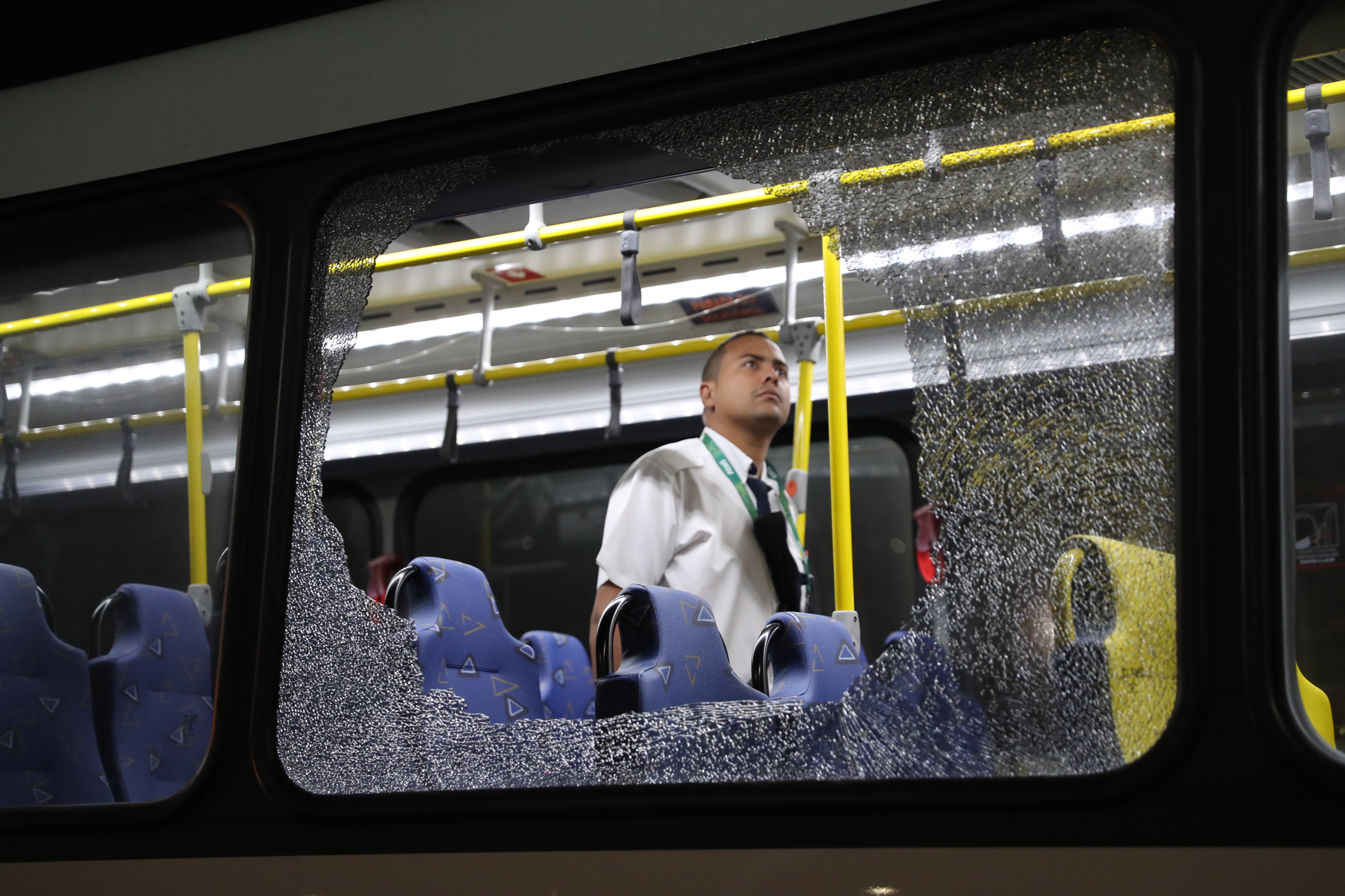 The damages to the windows of an Olympic journalists bus hit while driving on the transolympica highway are inspected by an official in Rio de Janeiro on August 9, 2016.  - Argentina OUT - LA NACION    / AFP PHOTO / LA NACION / Maximiliano AMENA / Argentina OUT