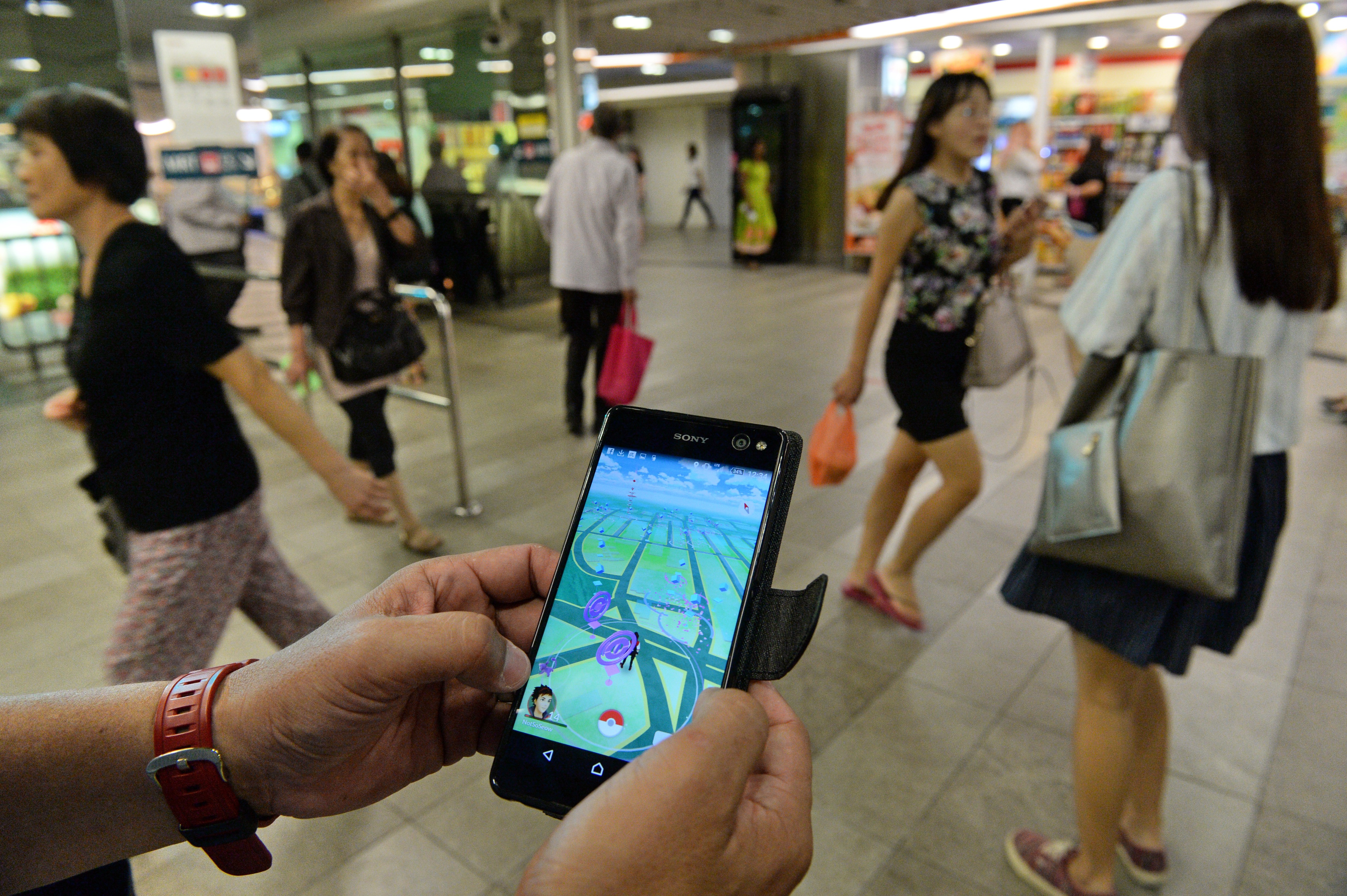 A man shows the Pokemon Go game on his smartphone while hunting outside a SMRT train station in Singapore on August 11, 2016. Pokemon Go was available in nine countries on August 6, including Singapore. / AFP PHOTO / ROSLAN RAHMAN